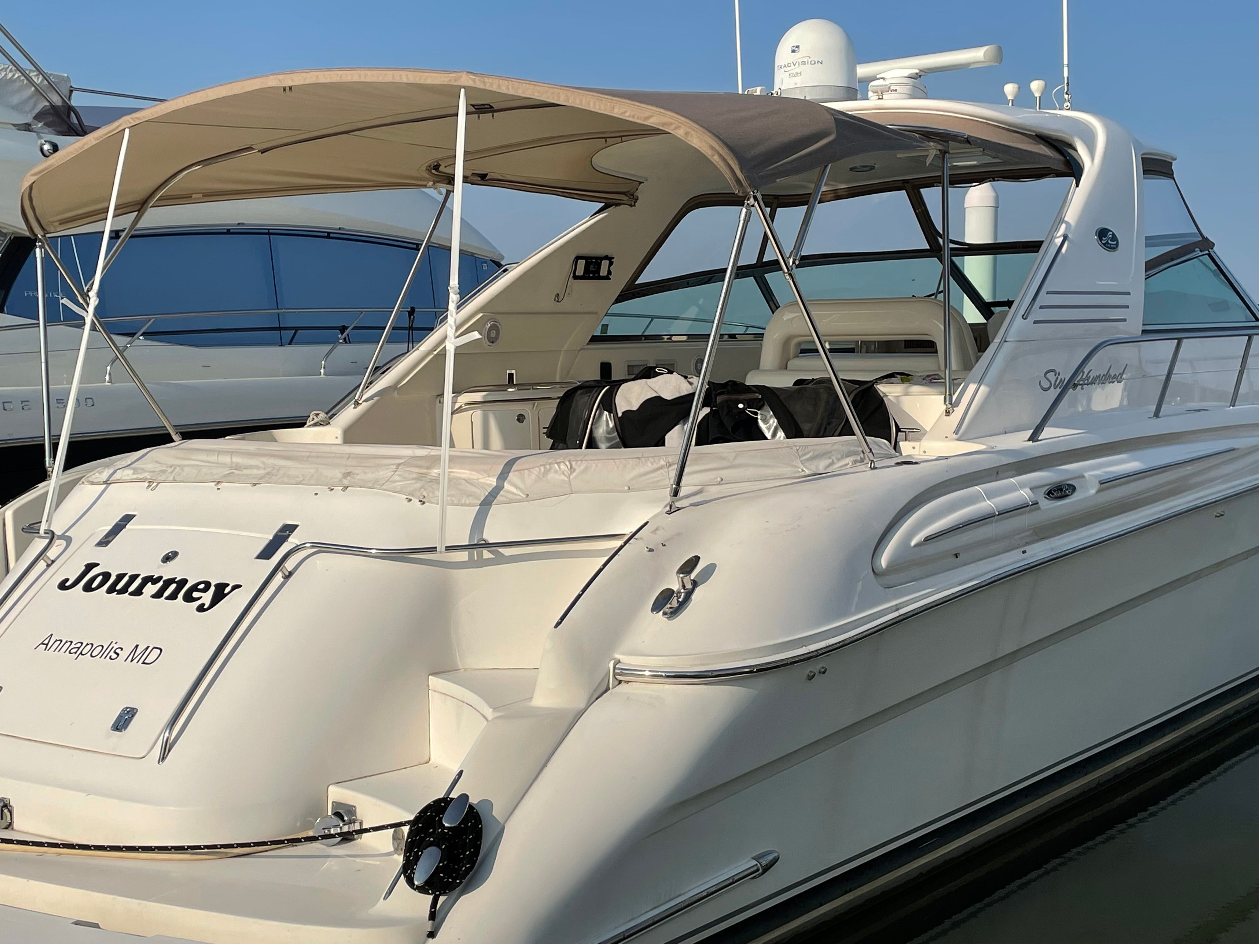 A 2003 Sea Ray S600 Sunsport with a beige sunshade, docked at the harbor.