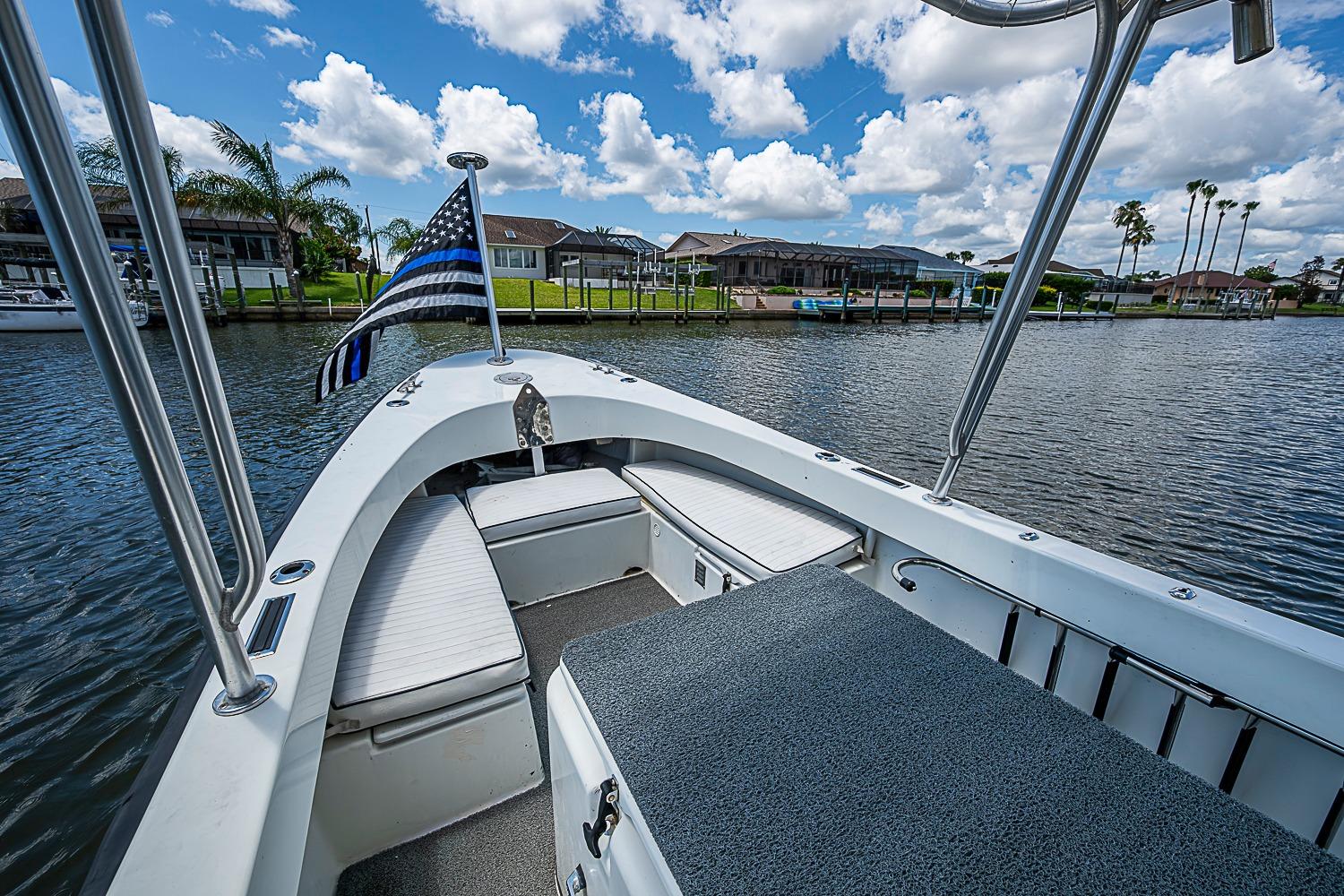 Custom 1969 boat with flag on calm water, surrounded by houses and palm trees.