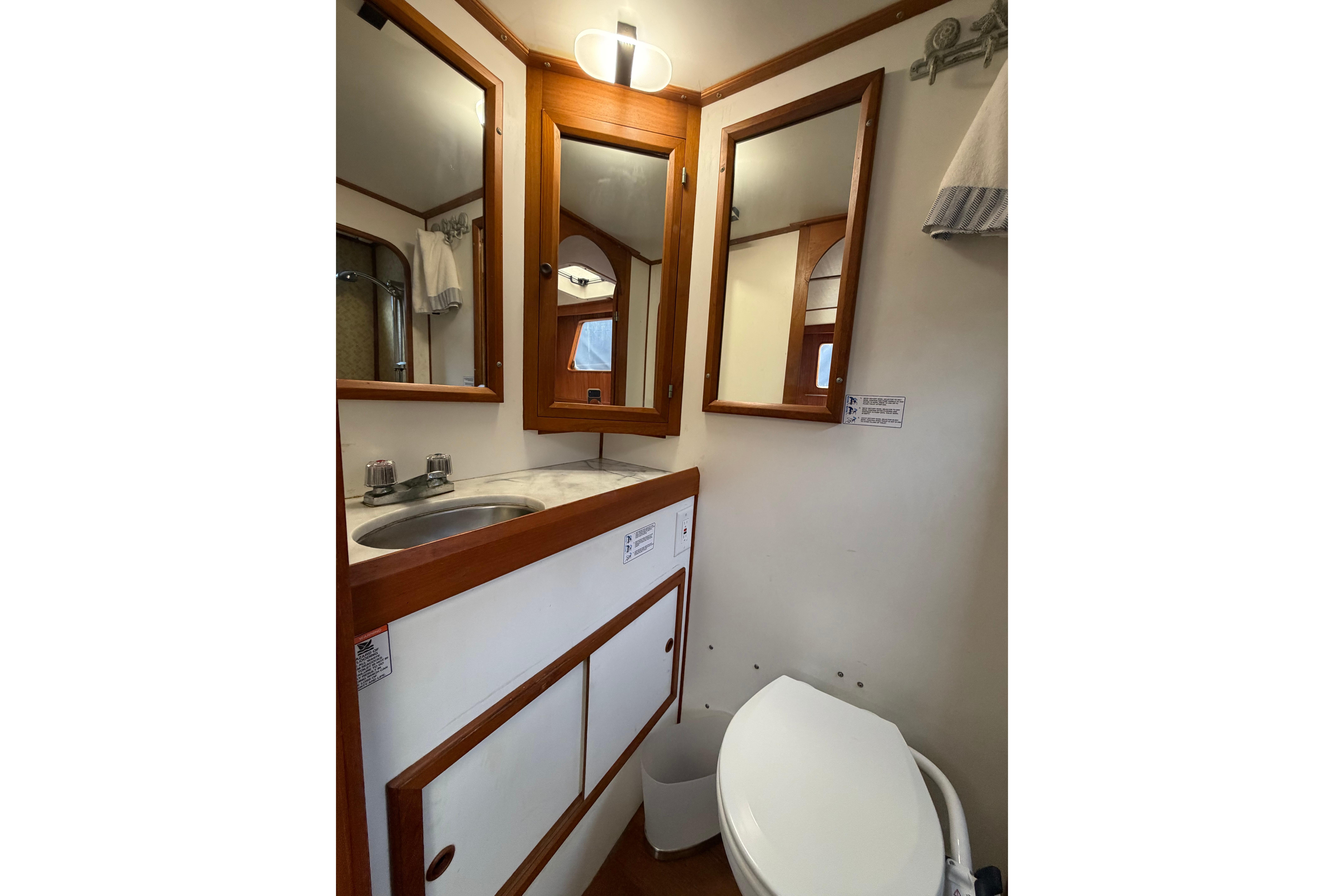 Compact bathroom in 1988 Monk 36 boat with sink, mirror, and toilet.