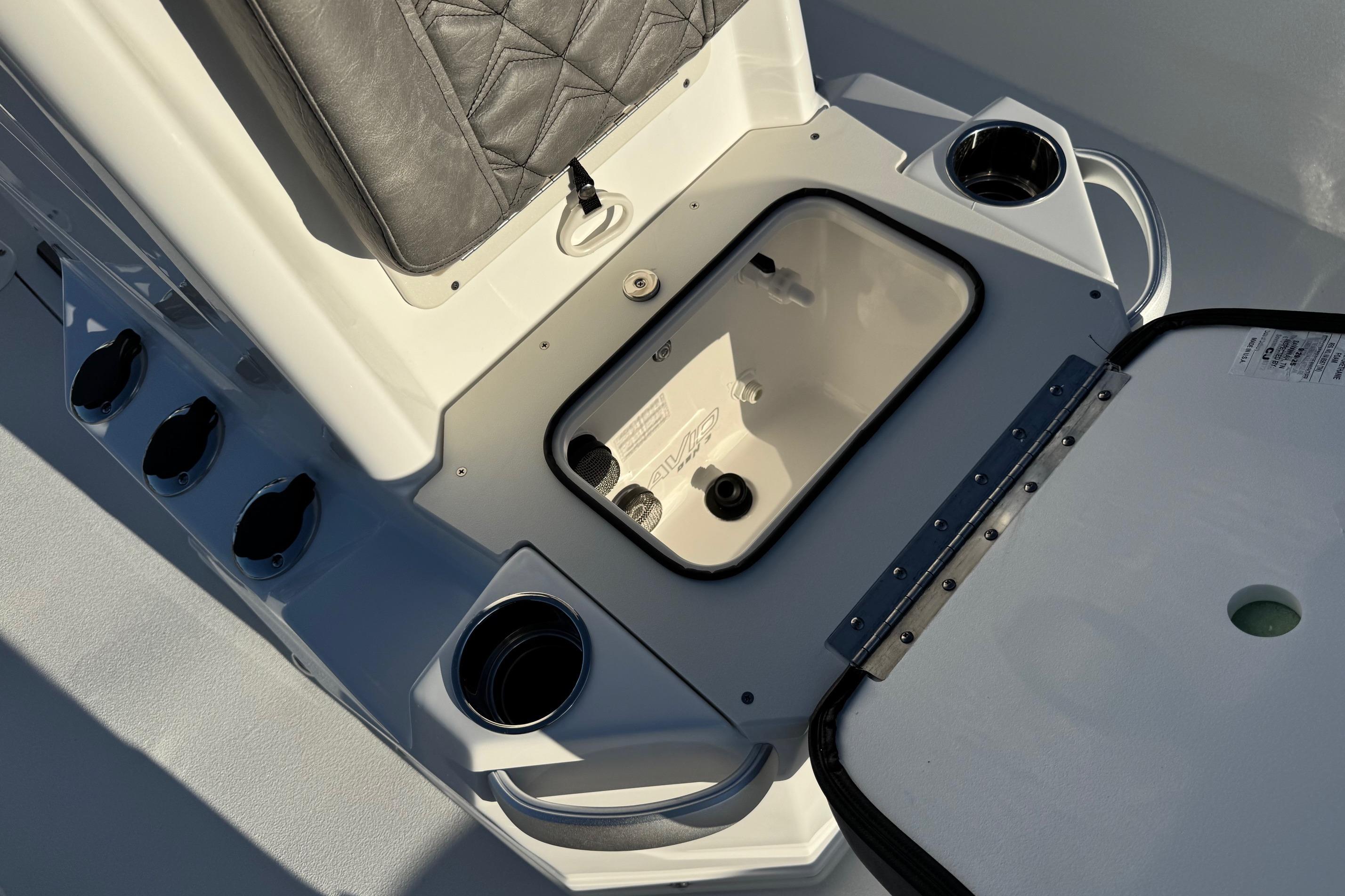 Avid 23 Mag 2025 boat interior with storage compartment and cup holders.