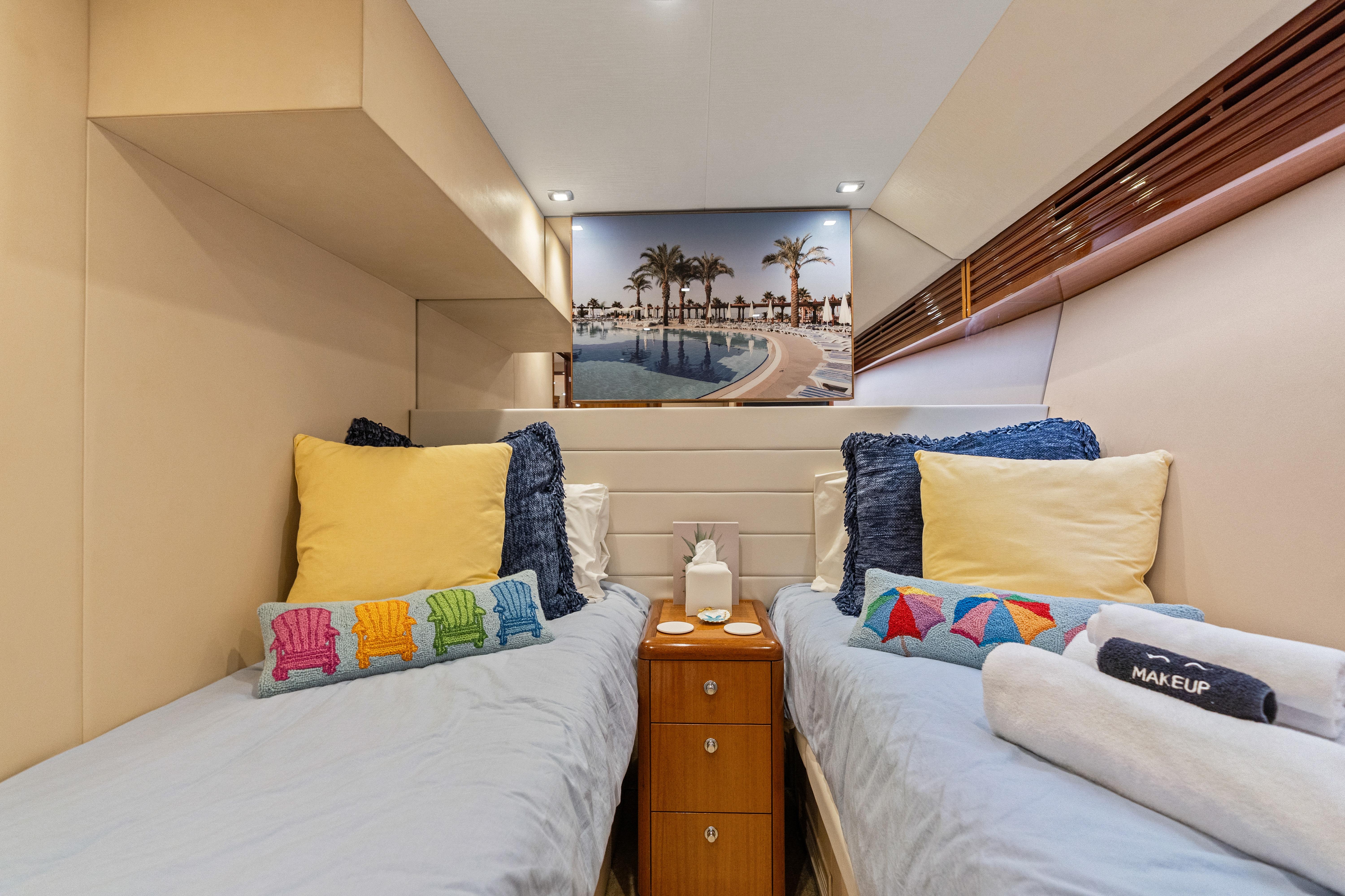 Luxurious twin cabin interior of 2008 Hatteras 64 Motor Yacht with colorful pillows.