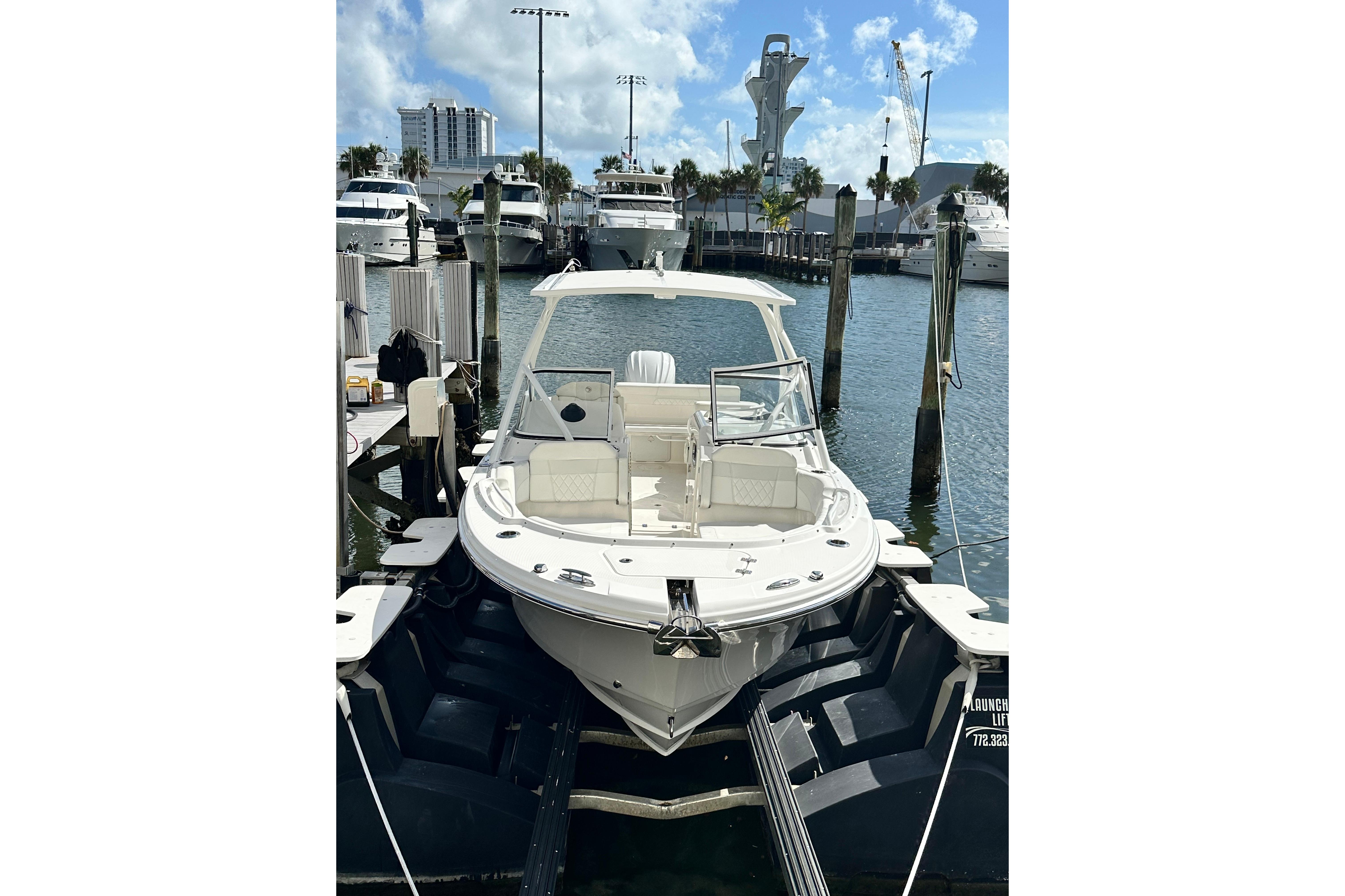 2023 Edgewater 248CX Crossover boat docked at marina under clear sky.