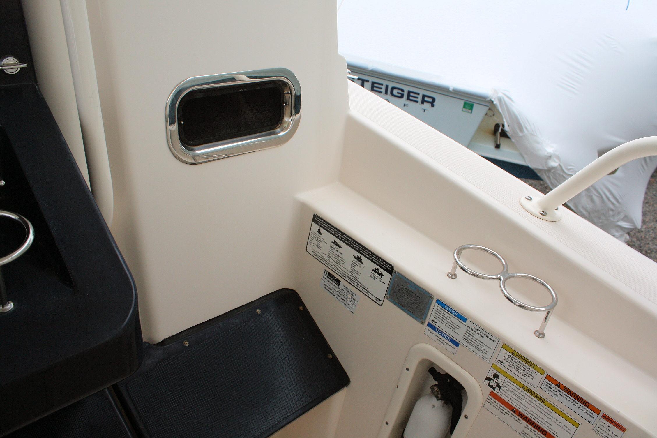 Interior view of a 2013 Pursuit ST 310 Sport boat, featuring safety labels and cup holders.