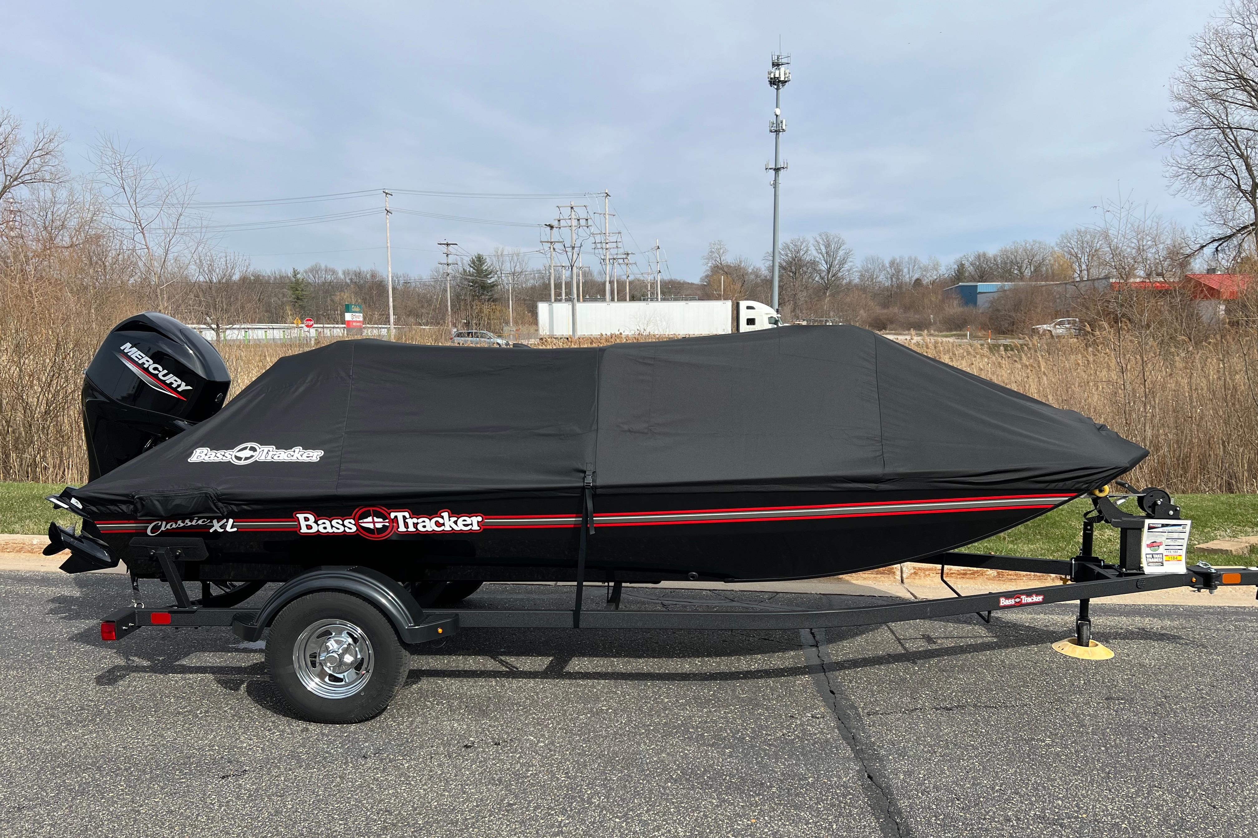 2026 Tracker Bass Tracker Classic XL boat covered, on trailer, parked outdoors.