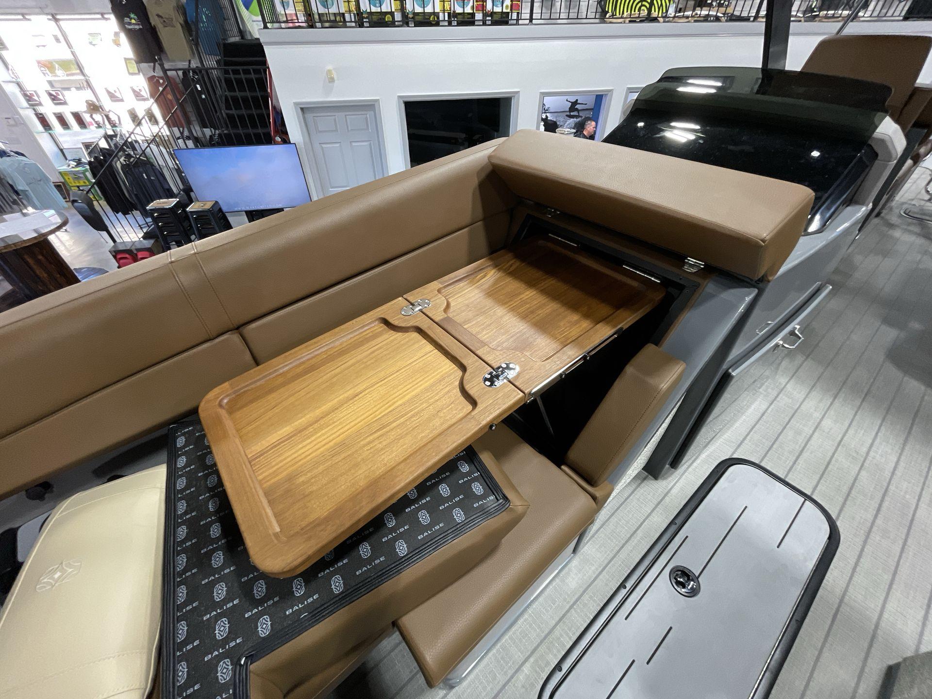 Interior of 2025 Balise Horizon 26C boat with foldable wooden table and brown seating.