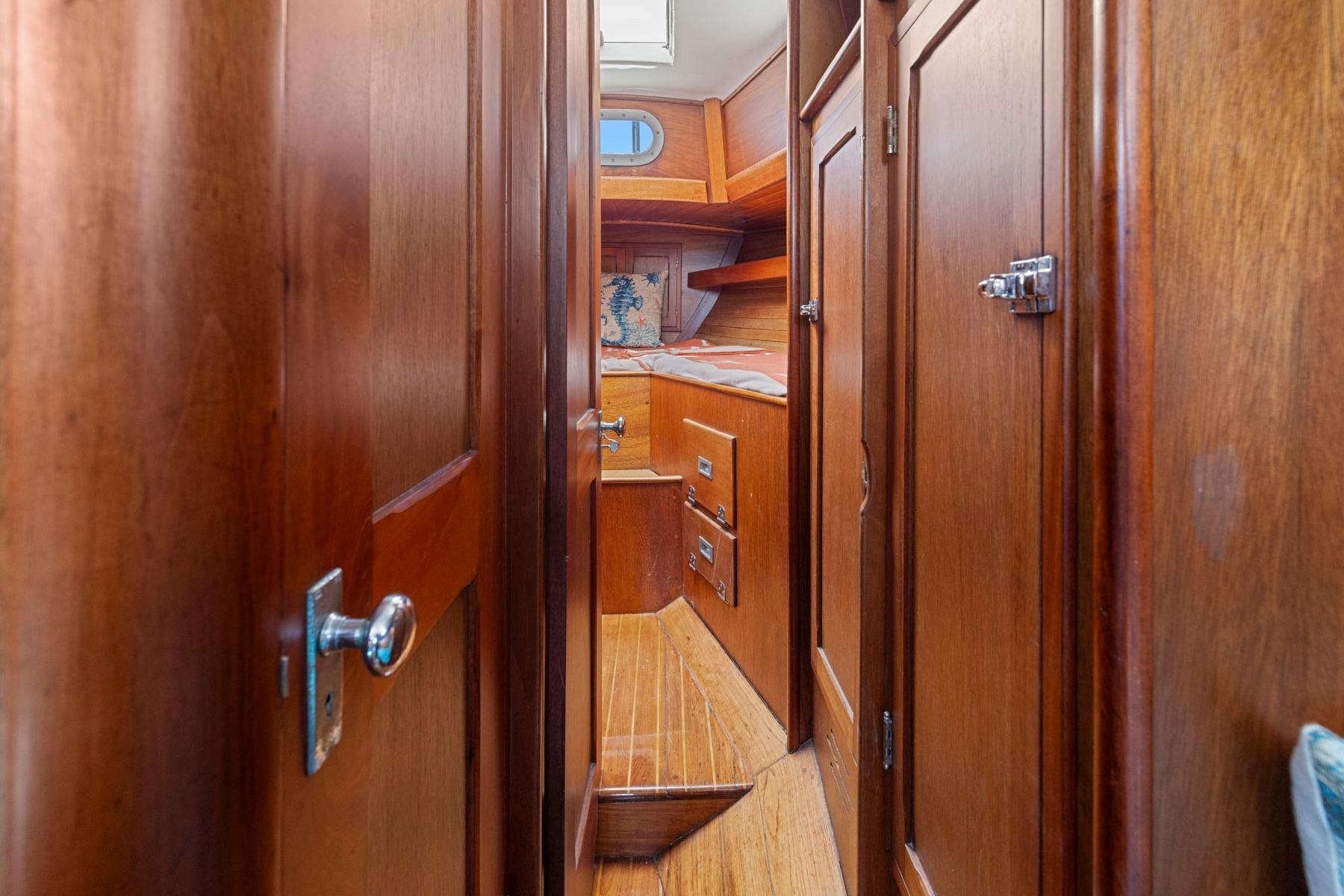 Interior of 1964 Hinckley Pilot 35 sailboat with wooden cabinetry and cozy sleeping area.
