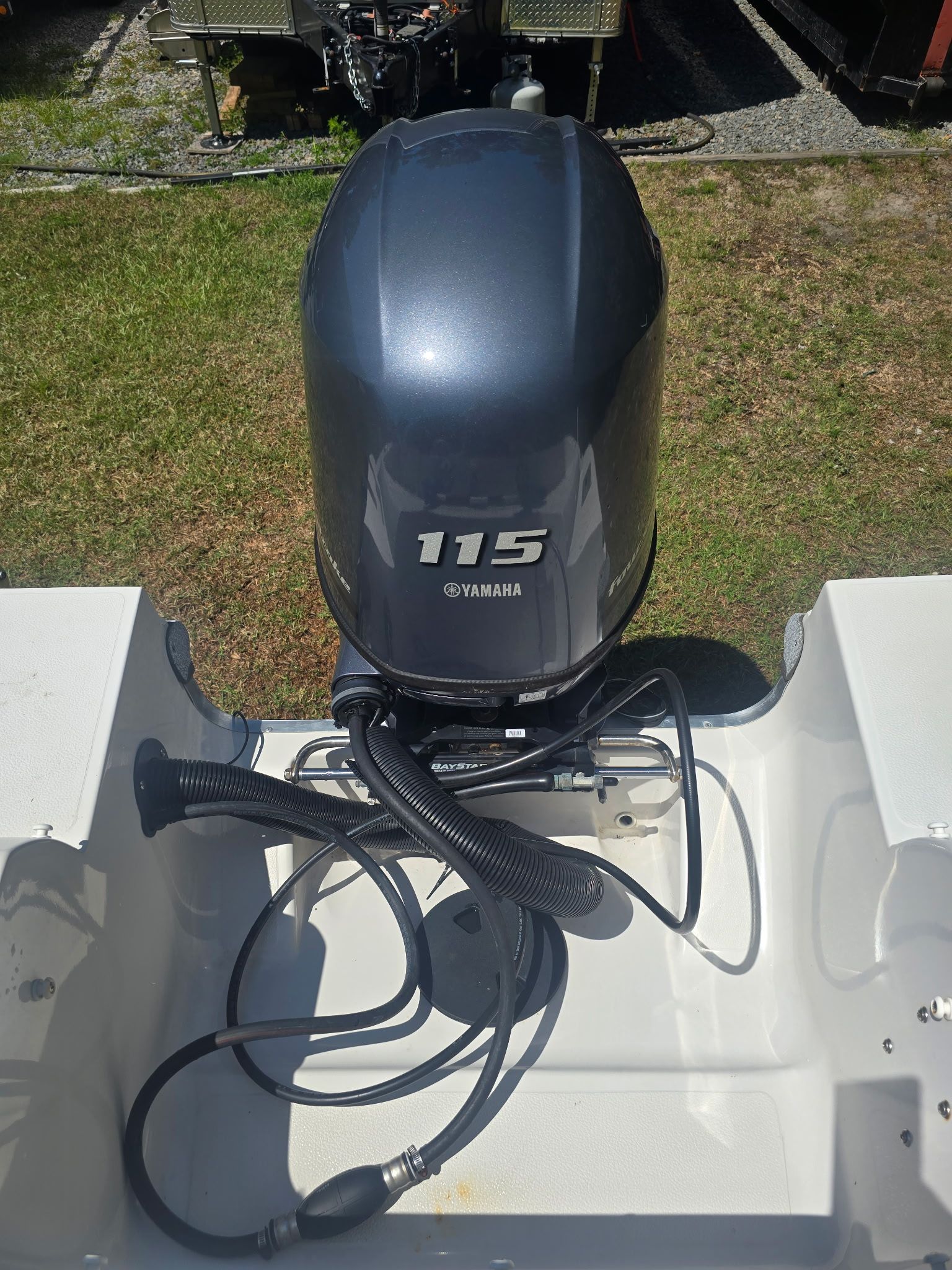 A Yamaha 115 outboard motor is mounted on a boat sitting on grass.