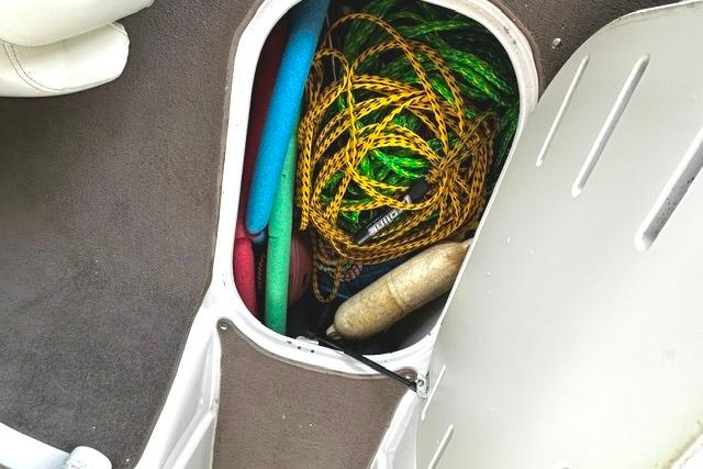 Storage compartment in 2007 Four Winns 200 Horizon boat with ropes and pool noodles.