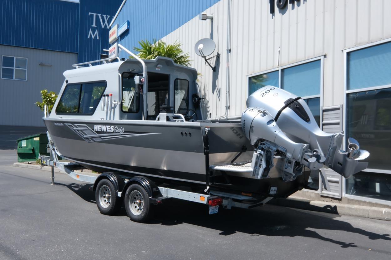 2018 Hewescraft 220 Ocean Pro ET Hardtop boat on trailer outside a building.