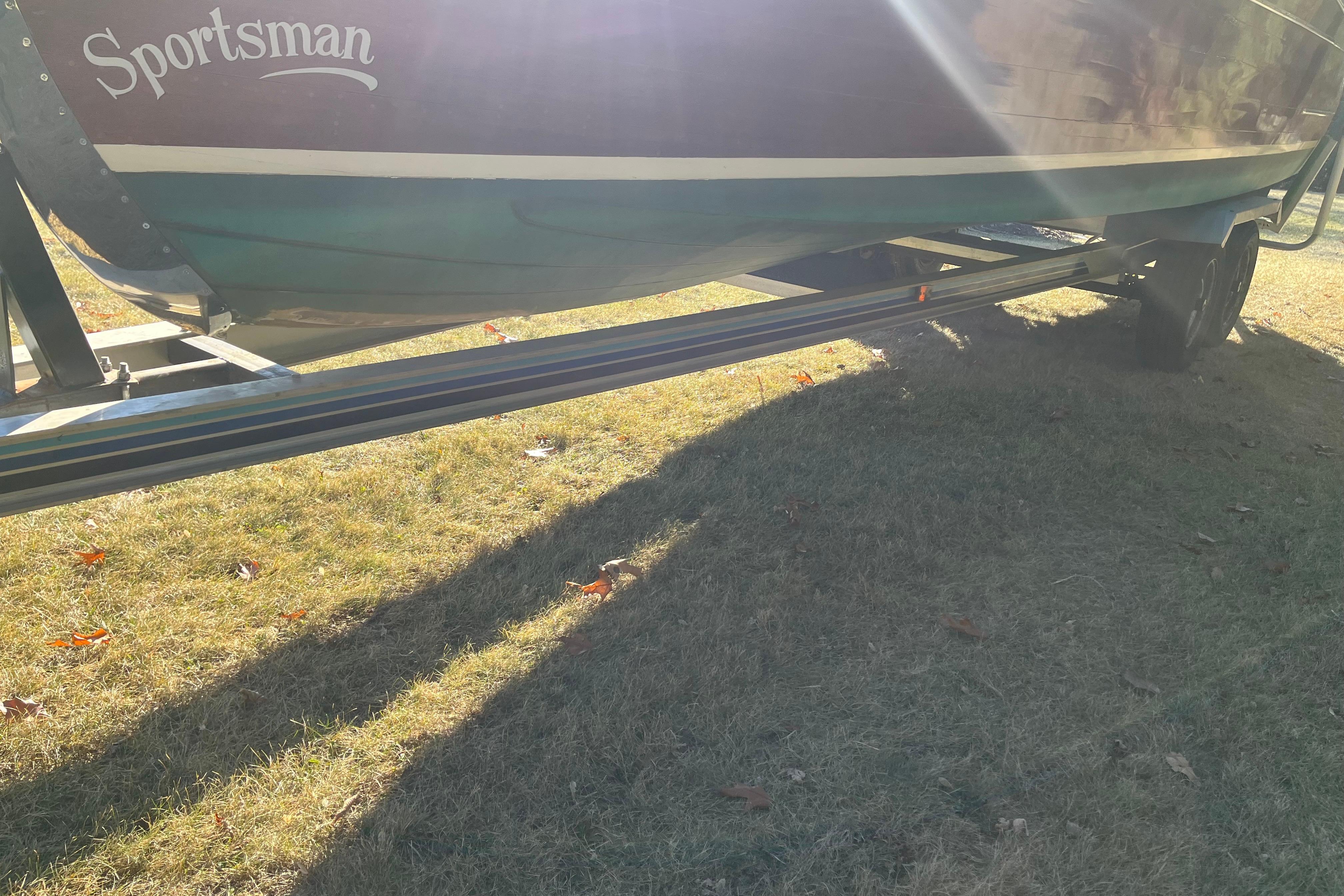 1938 Chris-Craft 28 Sportsman boat on trailer, sunlit on grassy ground.