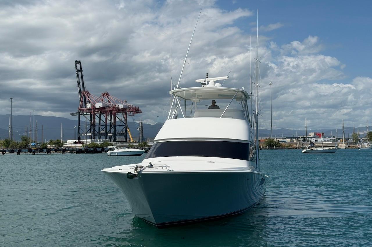 2012 Viking 50 Convertible yacht in a harbor with cranes and cloudy sky.