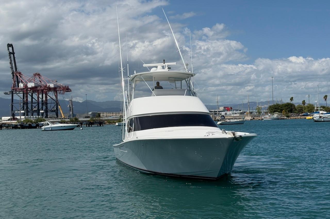 2012 Viking 50 Convertible yacht in a harbor with cranes and boats.
