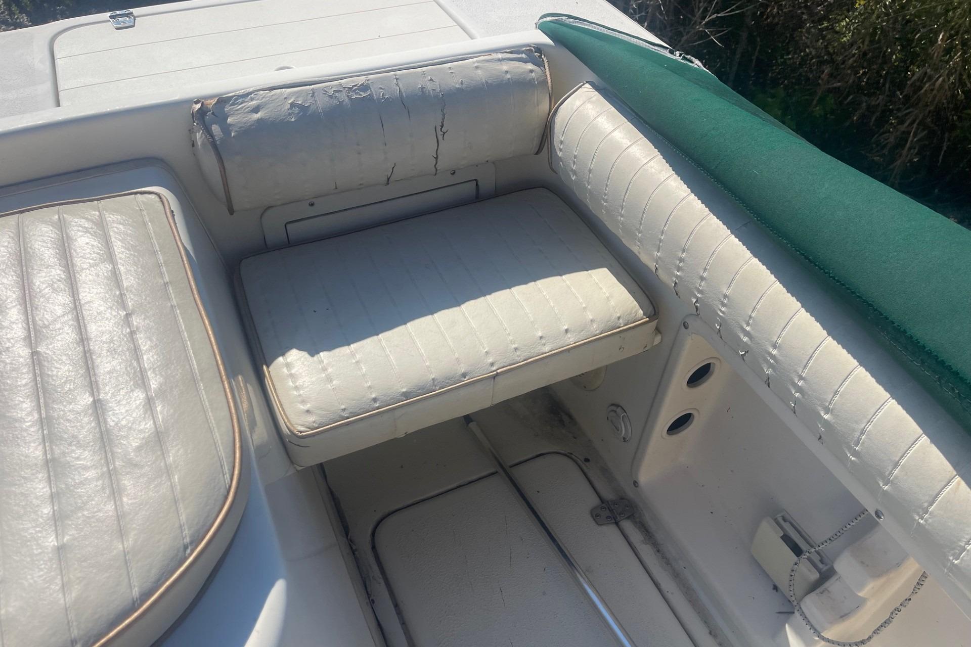 Worn seating area on 2000 Seamaster 2388 WA boat, featuring white upholstery and green trim.