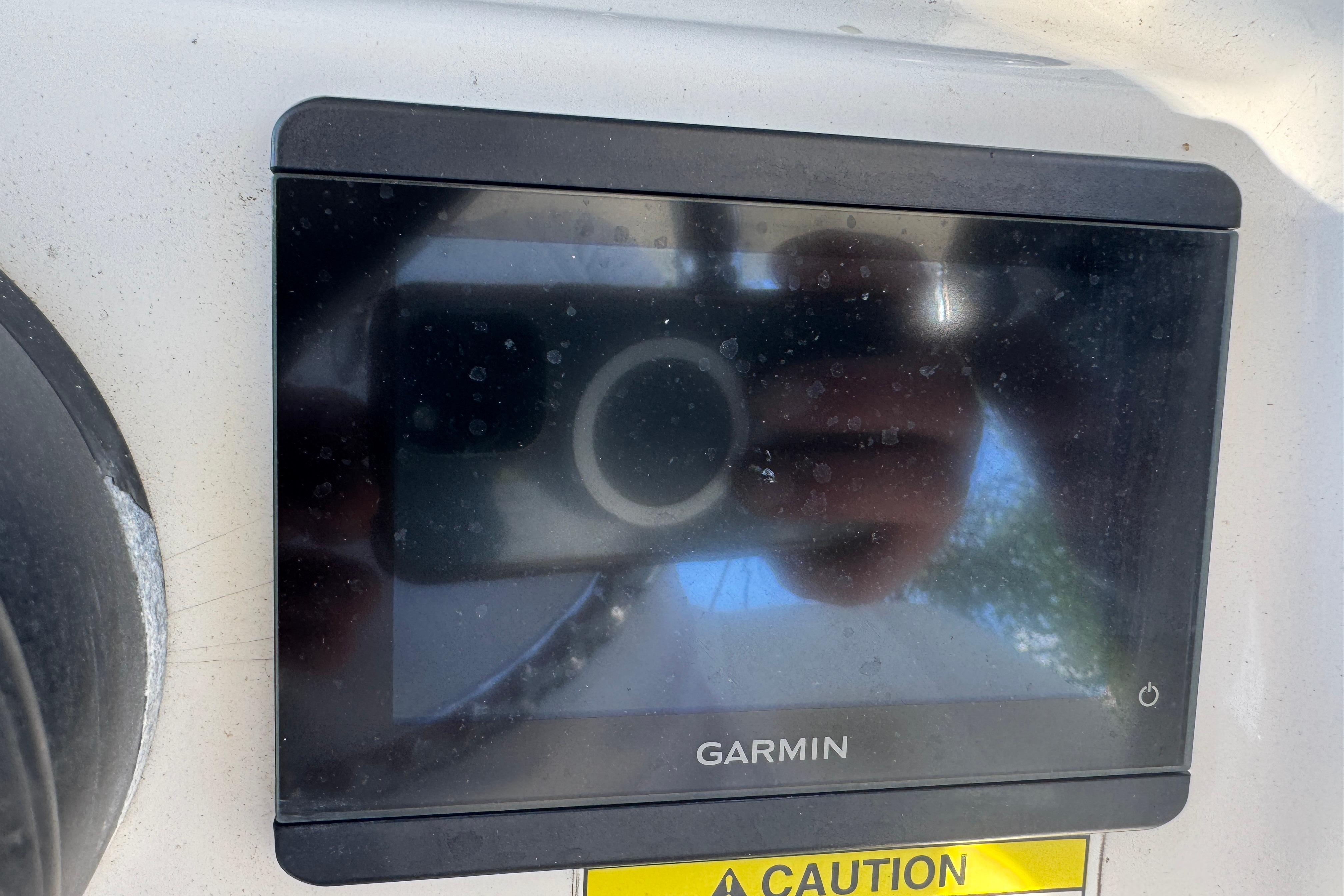 Garmin display on 2014 Boston Whaler 250 Outrage boat dashboard with caution label.