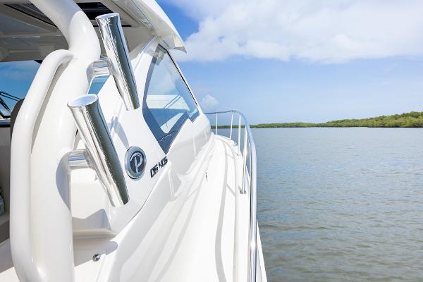 2025 Pursuit OS 405 boat cruising on a serene waterway under a clear blue sky.