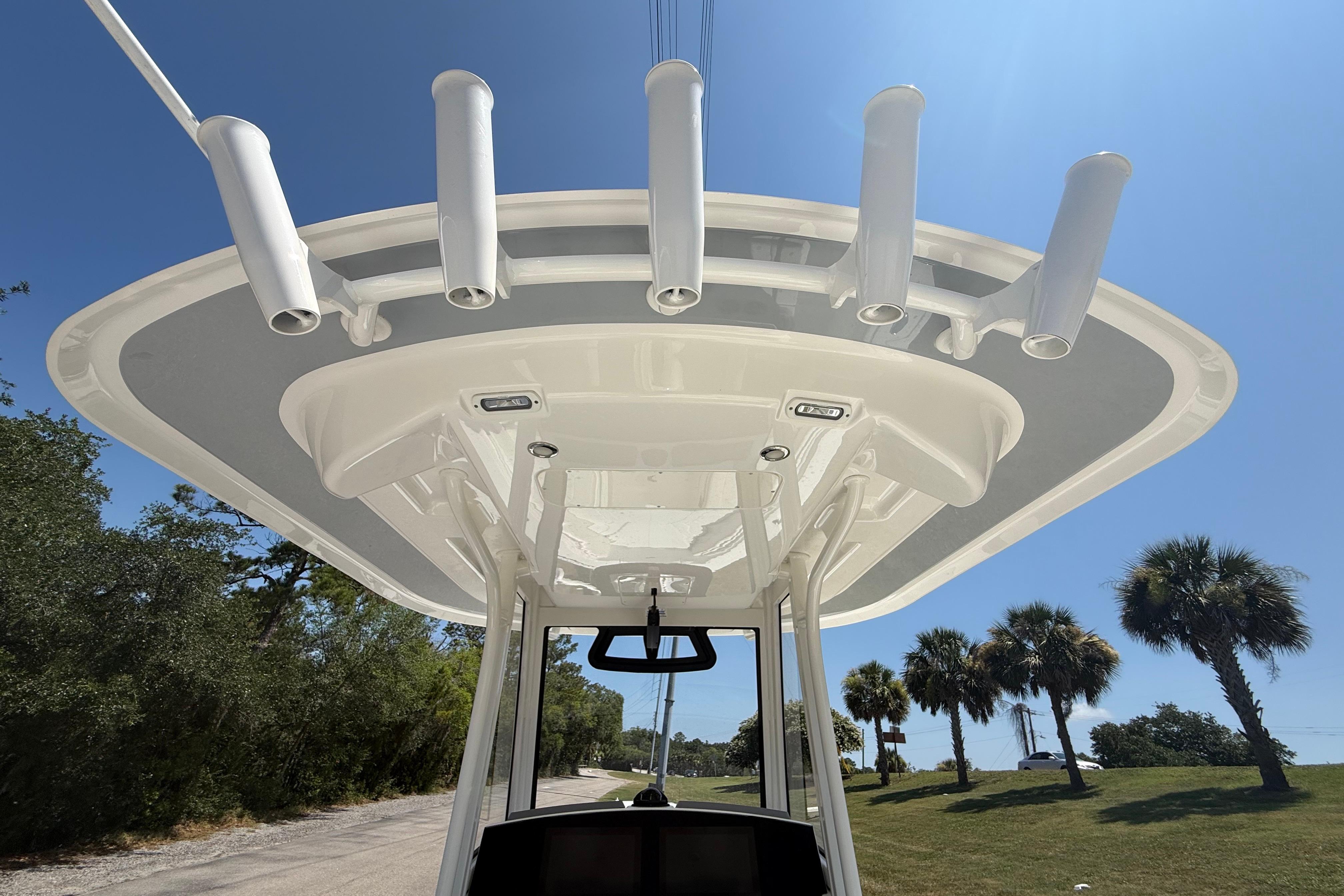 2023 Regulator 26XO boat T-top with rod holders under clear blue sky.
