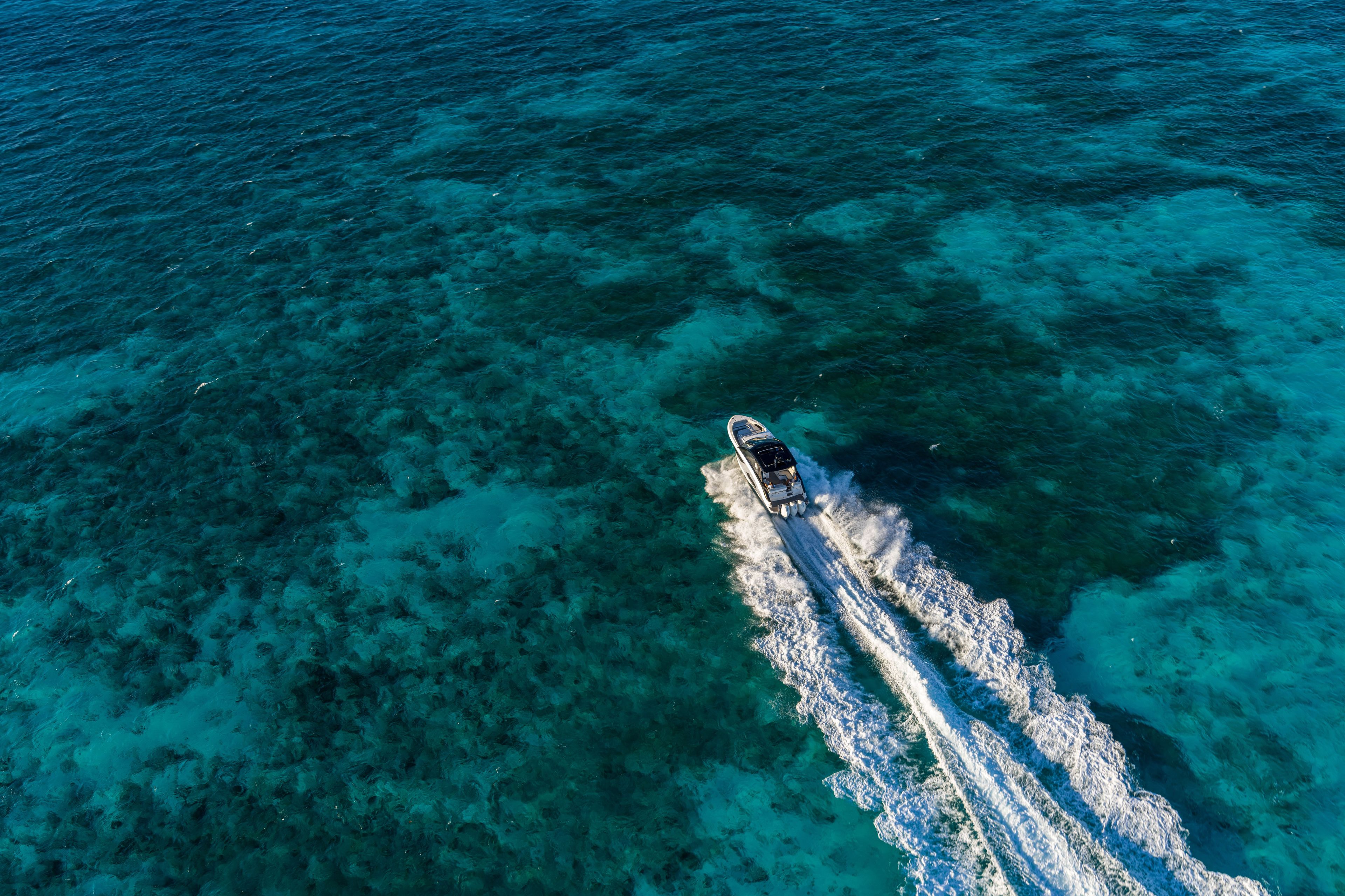 Aerial view of a boat on clear blue water with visible wake.
