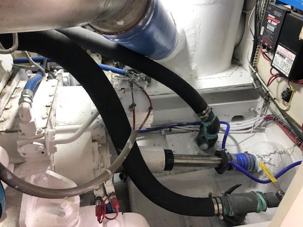 Engine room of a 1997 Bertram Convertible boat with hoses and mechanical components.