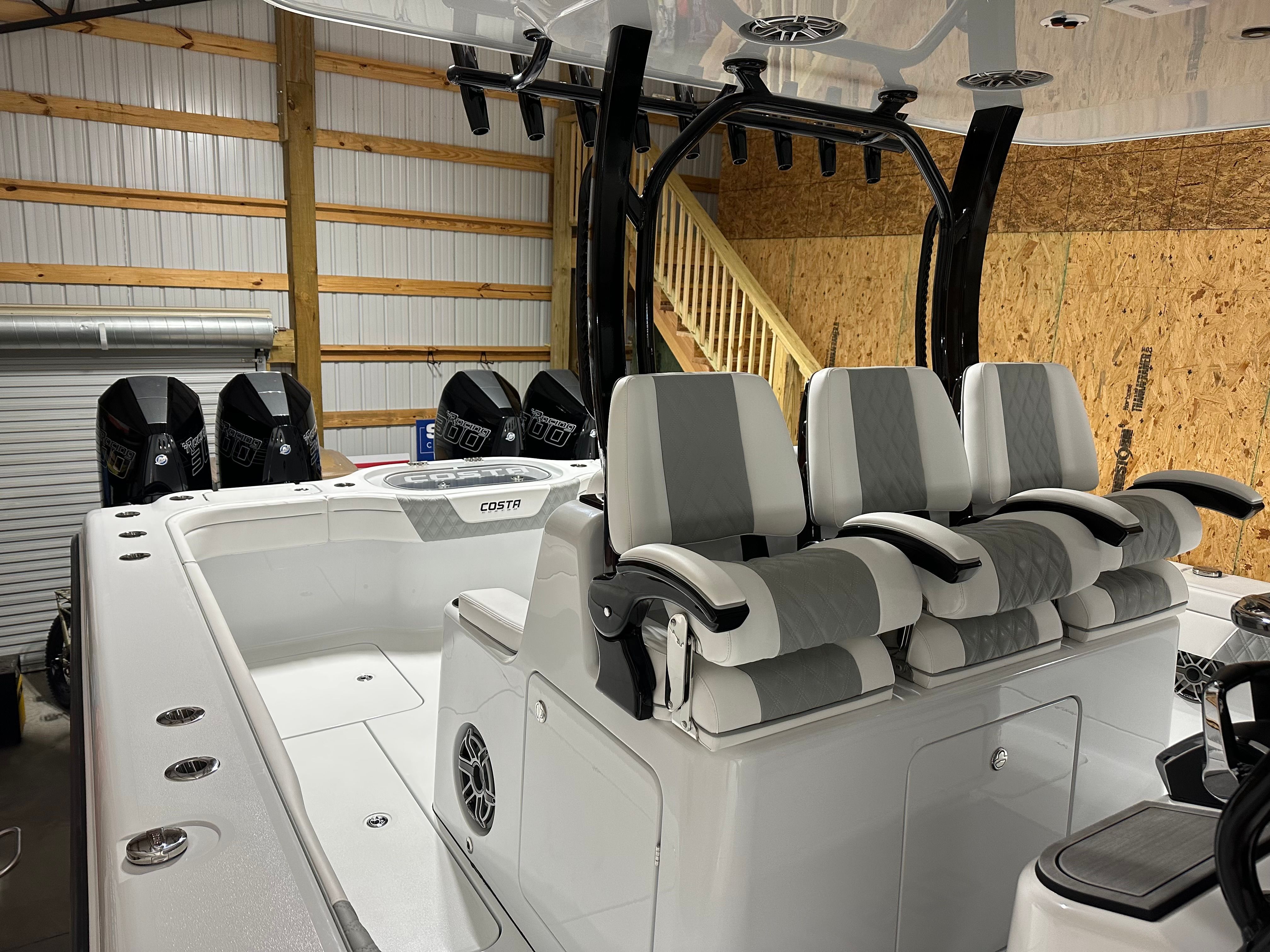 A modern boat with four seats and multiple engines in a storage facility.