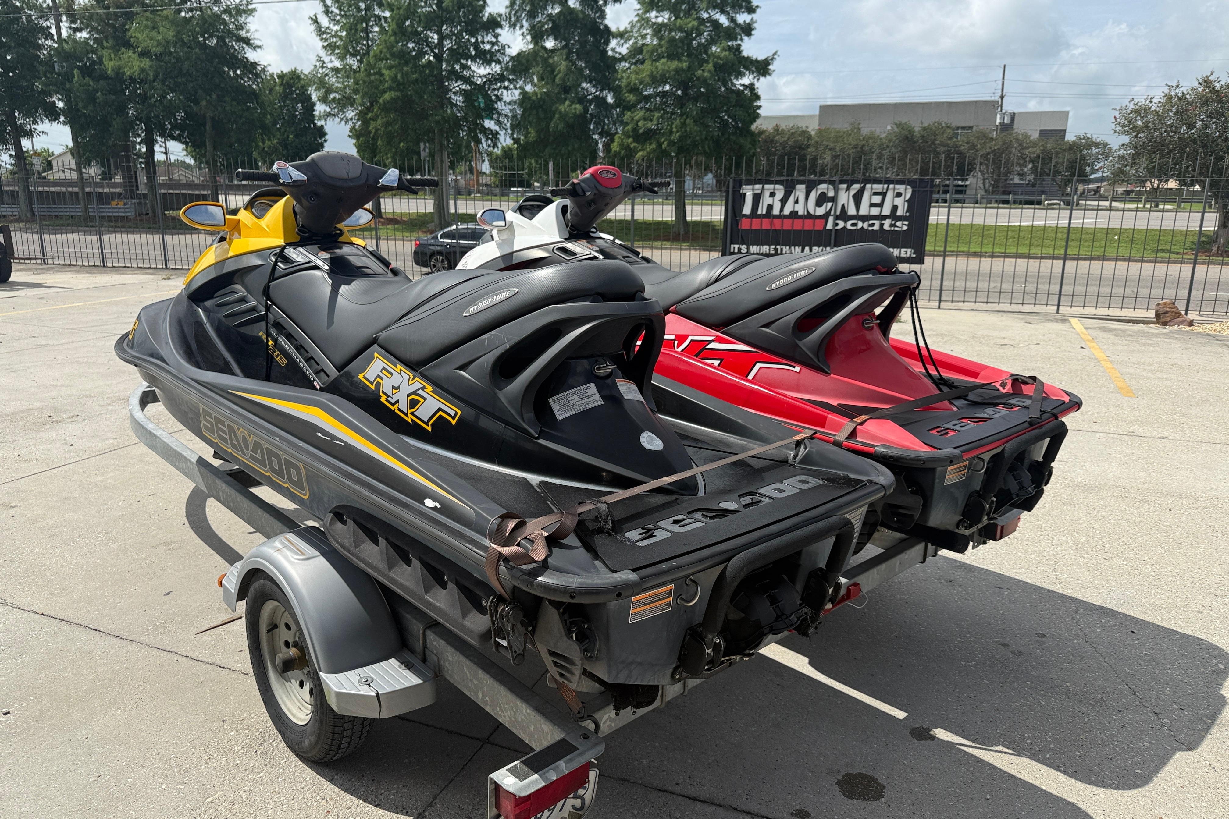 Two 2007 Sea-Doo RXT 215 jet skis on a trailer in a parking lot.