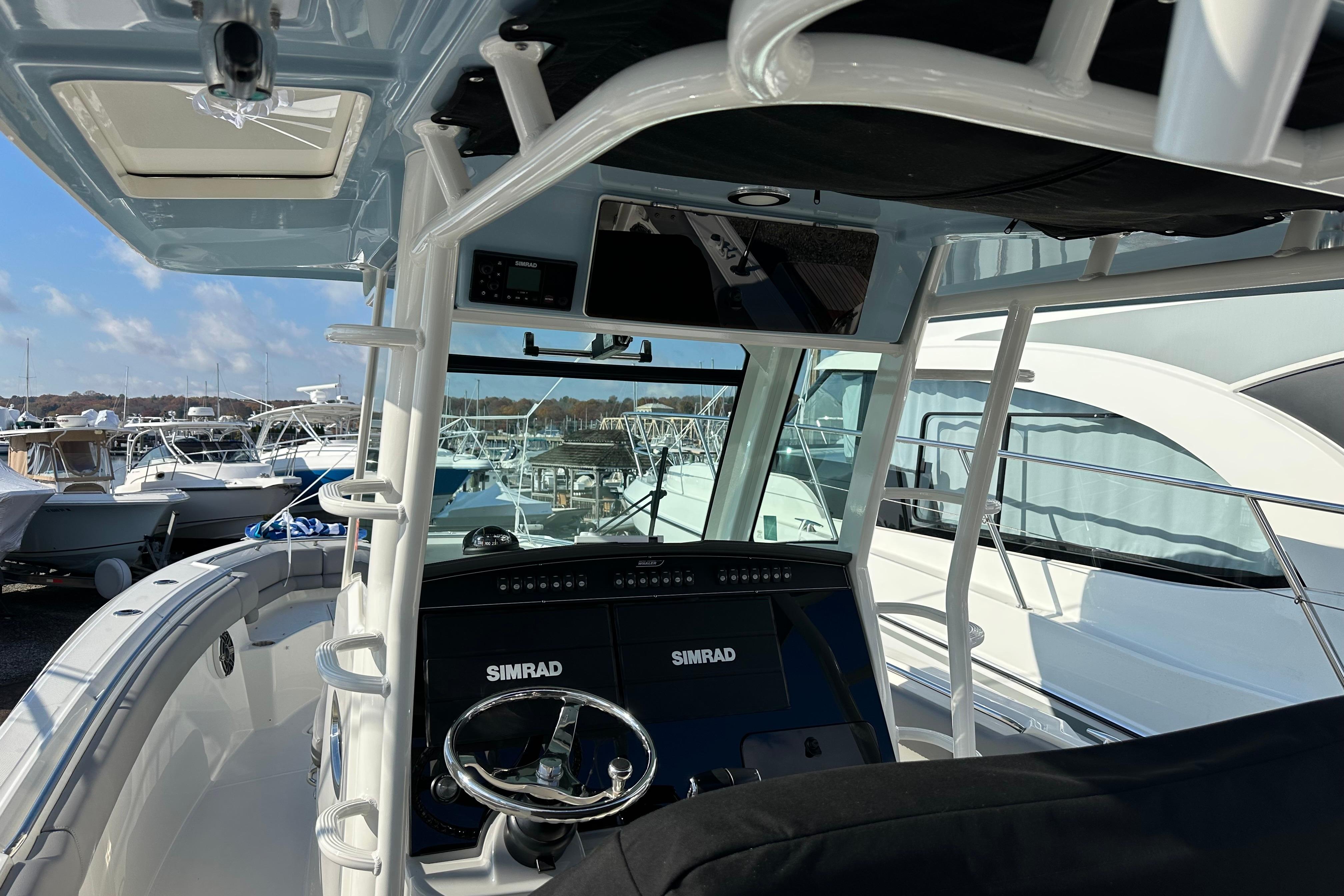 2023 Boston Whaler 330 Outrage boat interior with Simrad navigation system, docked among other boats.