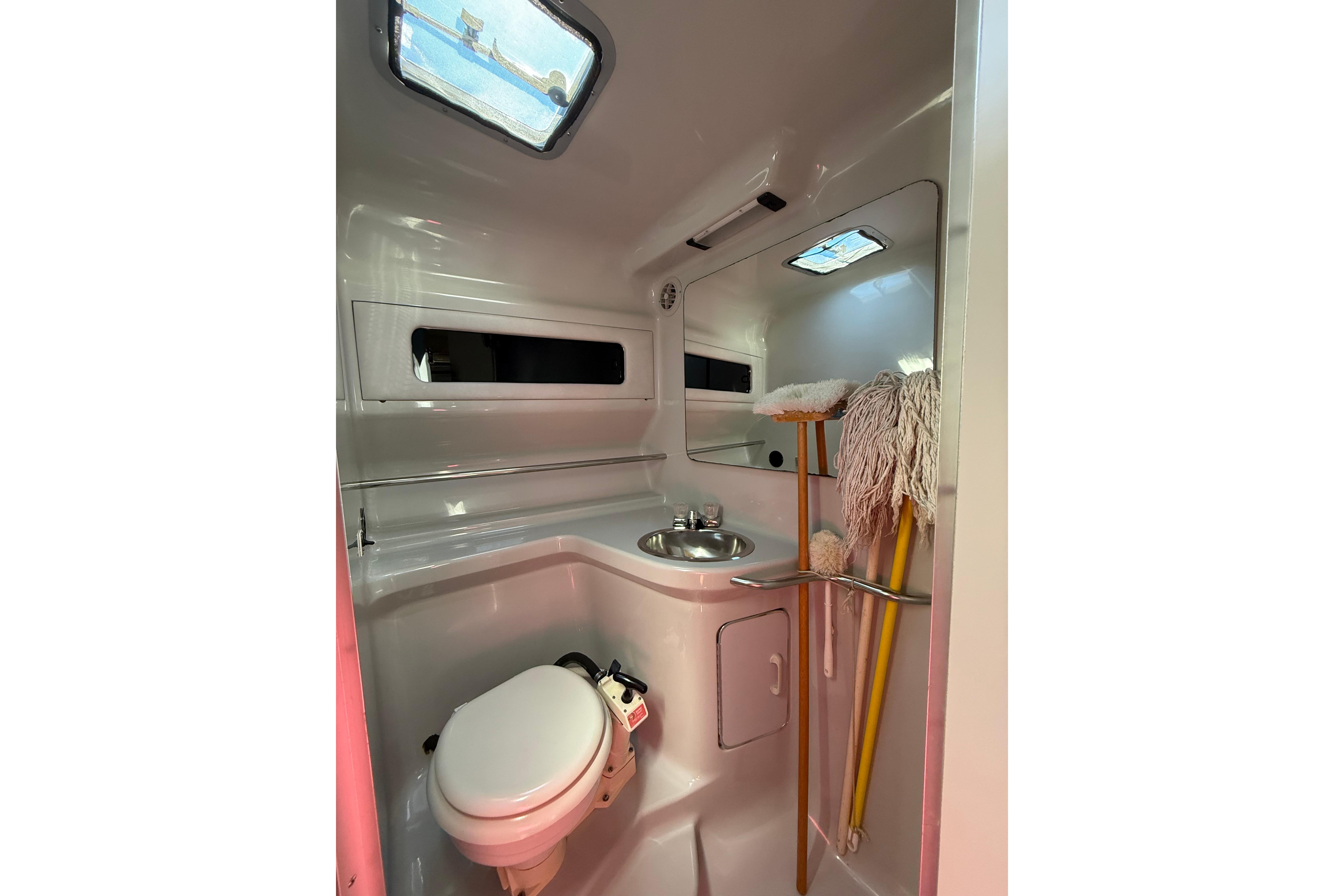 1990 Sea Ray 310 Express Cruiser bathroom with sink, toilet, and cleaning supplies.
