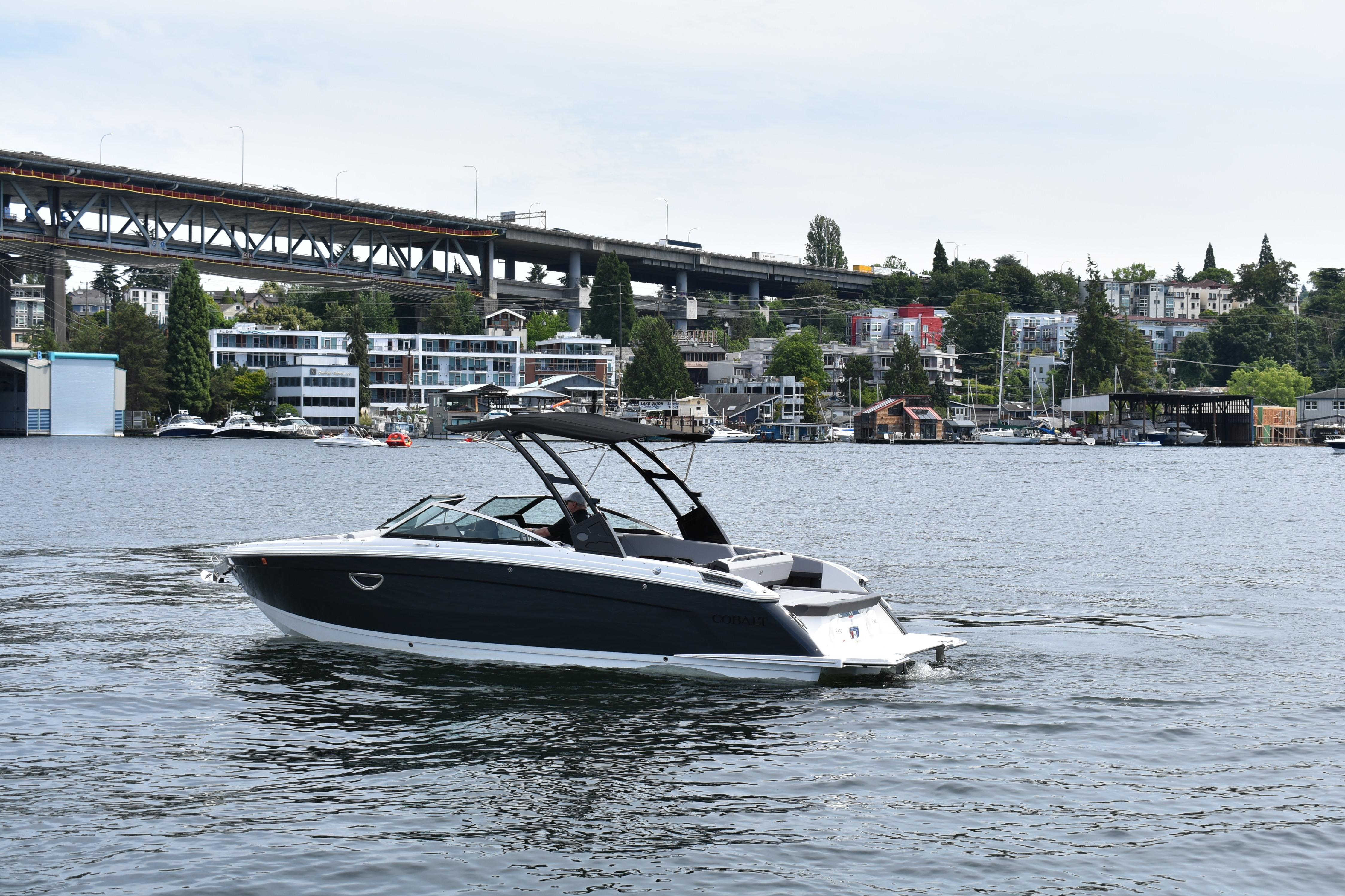 2023 Cobalt R8 boat cruising on a scenic urban waterway with bridge and buildings.
