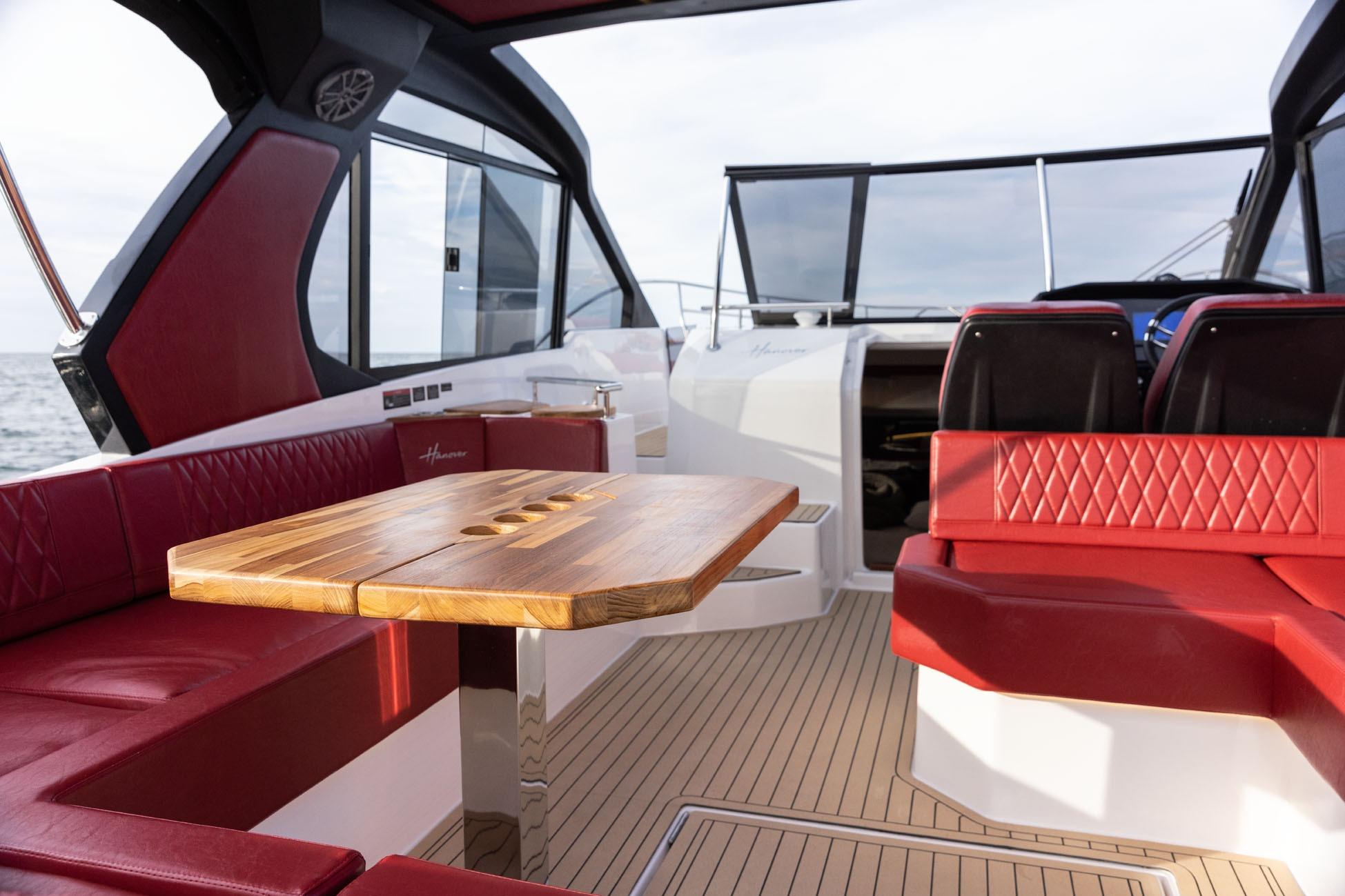 Luxurious 2026 Hanover 387 yacht interior with red seating and wooden table.