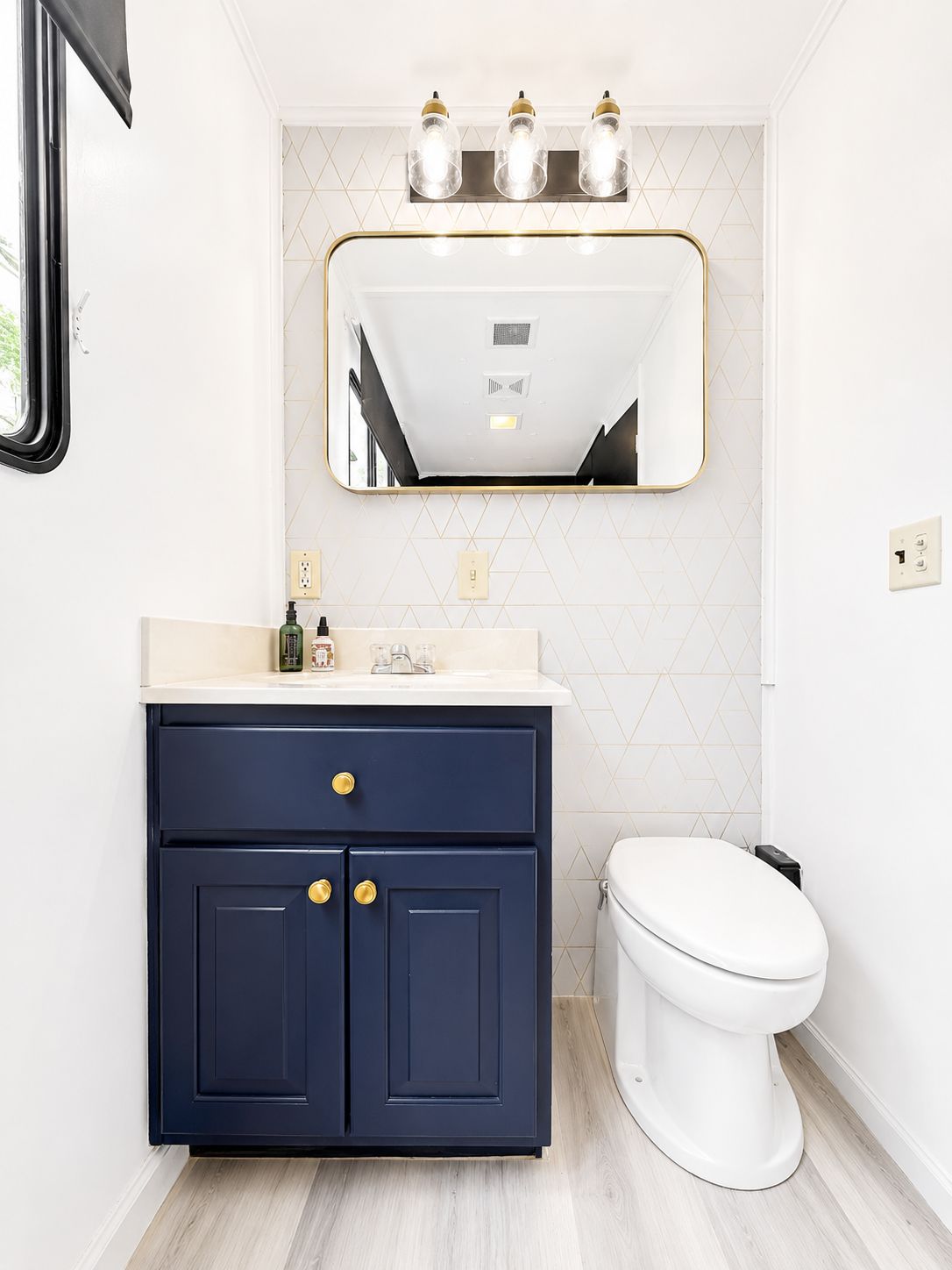 A modern bathroom with blue cabinets and a large mirror.