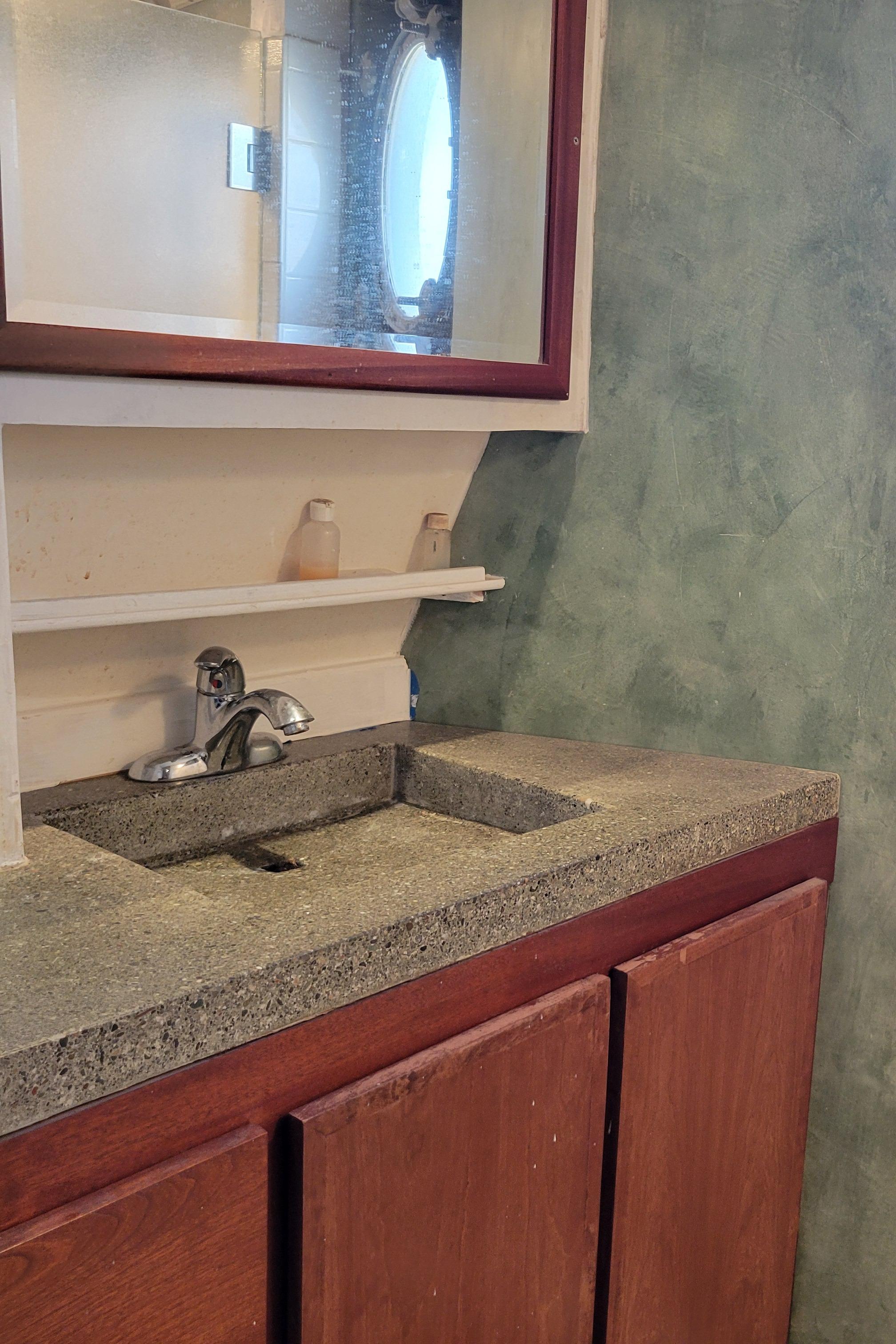 1979 Shrimper Conversion Trawler bathroom with wooden cabinets and stone countertop.
