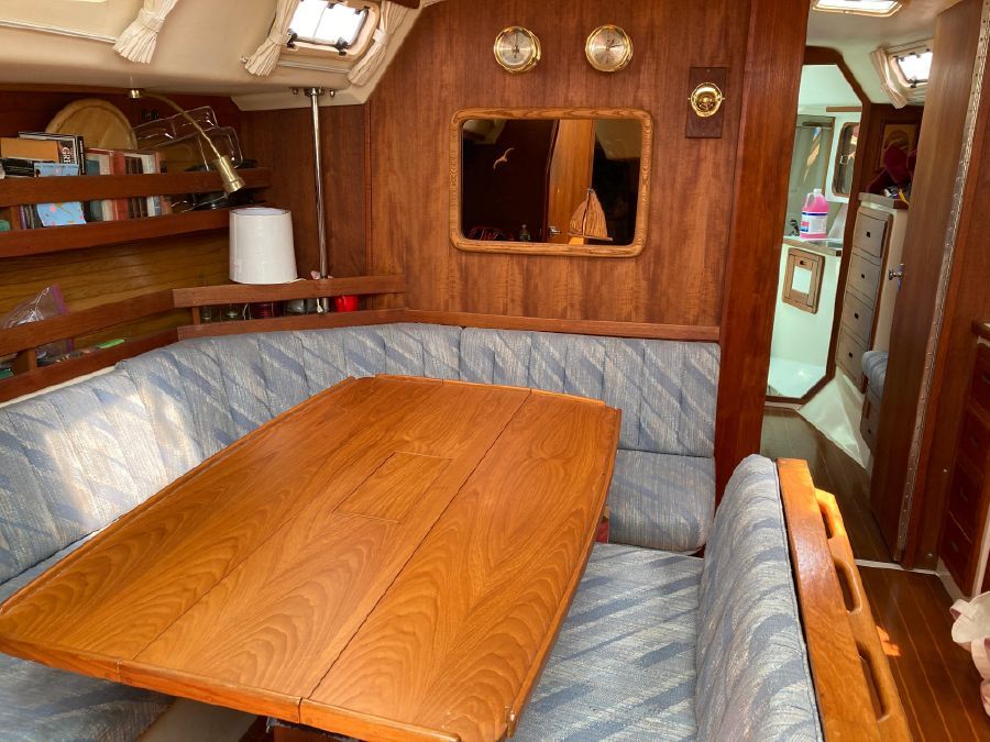 Interior of the 1990 Catalina 42 Tricabin with a wooden table and blue upholstery.