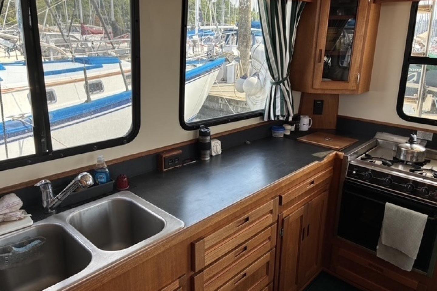 Interior of a 2000 Nordic Tug 37 boat kitchen with wooden cabinetry and dual sinks.
