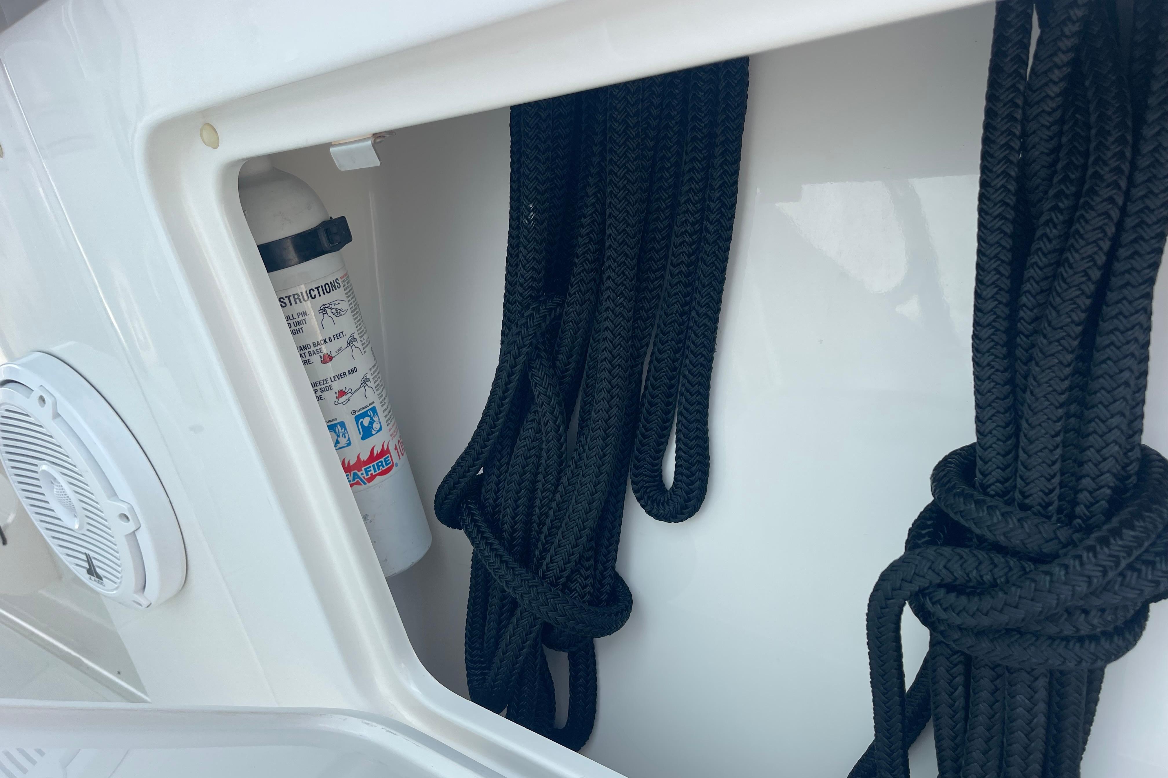 Storage compartment on a 2020 Jupiter 38 boat with ropes and a fire extinguisher.