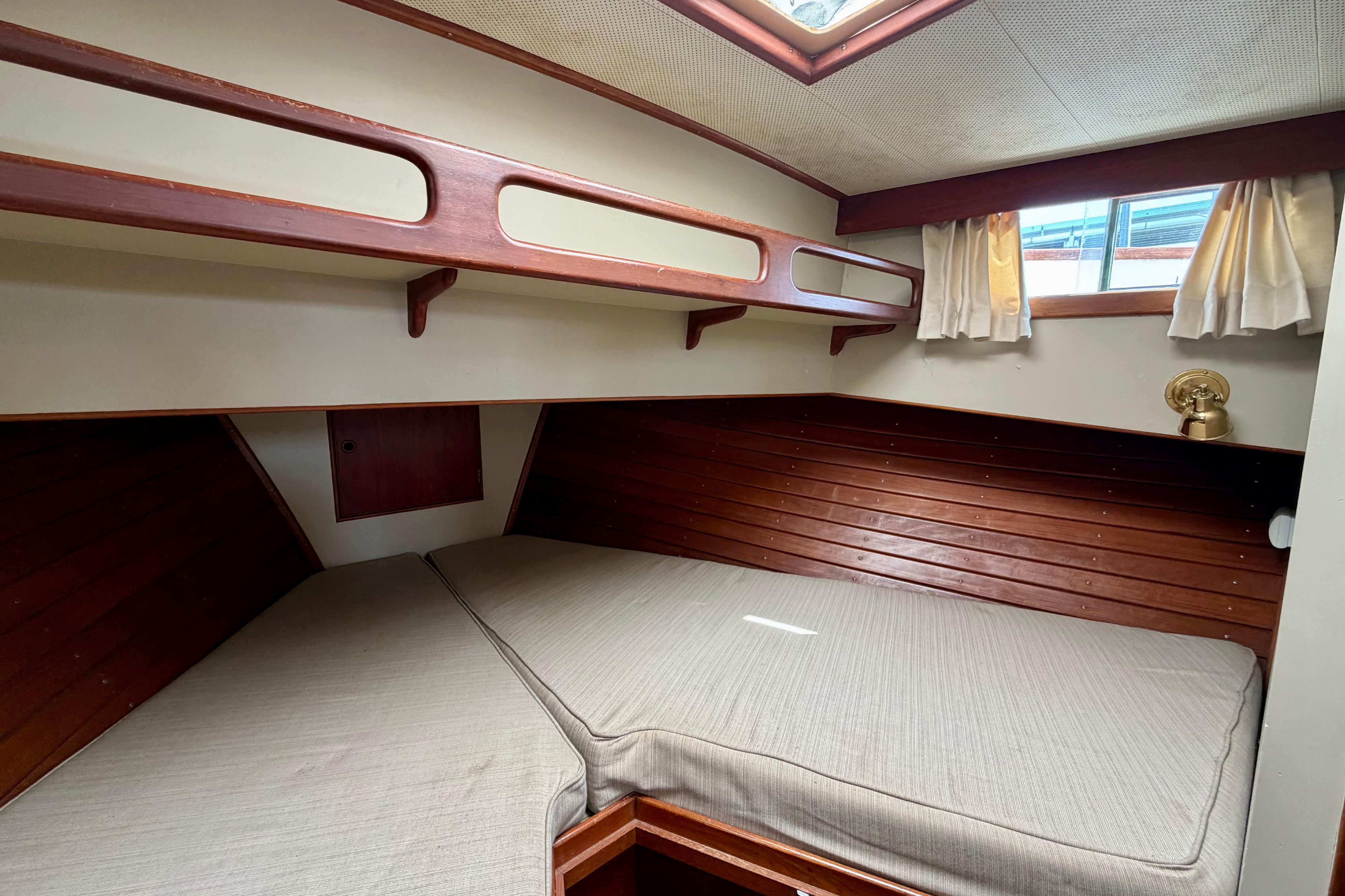 Cozy cabin interior of 1983 Grand Banks 32 Sedan with wooden accents and bedding.