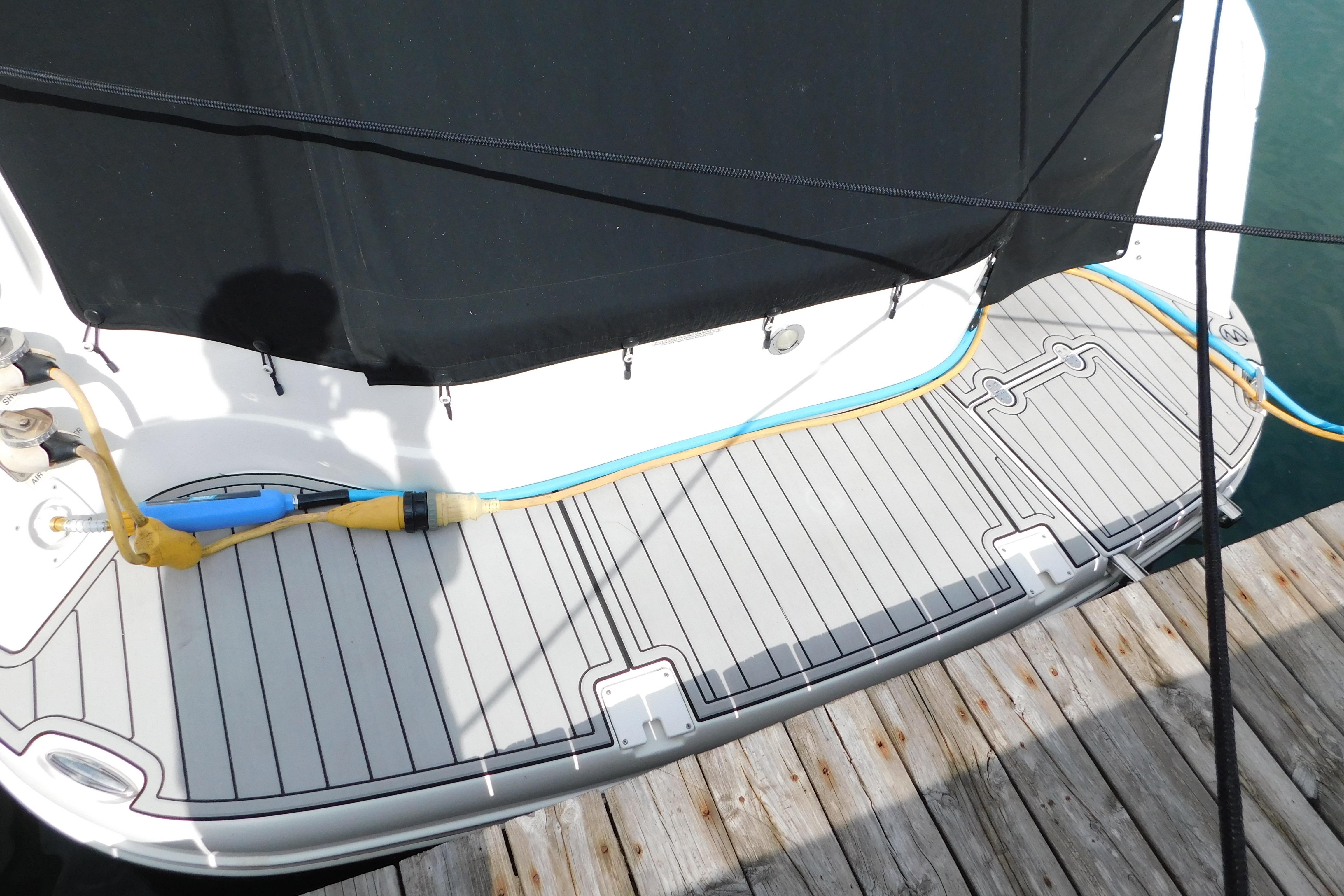 2017 Rinker EX 320 boat stern with dock, showing power cables and water hose.