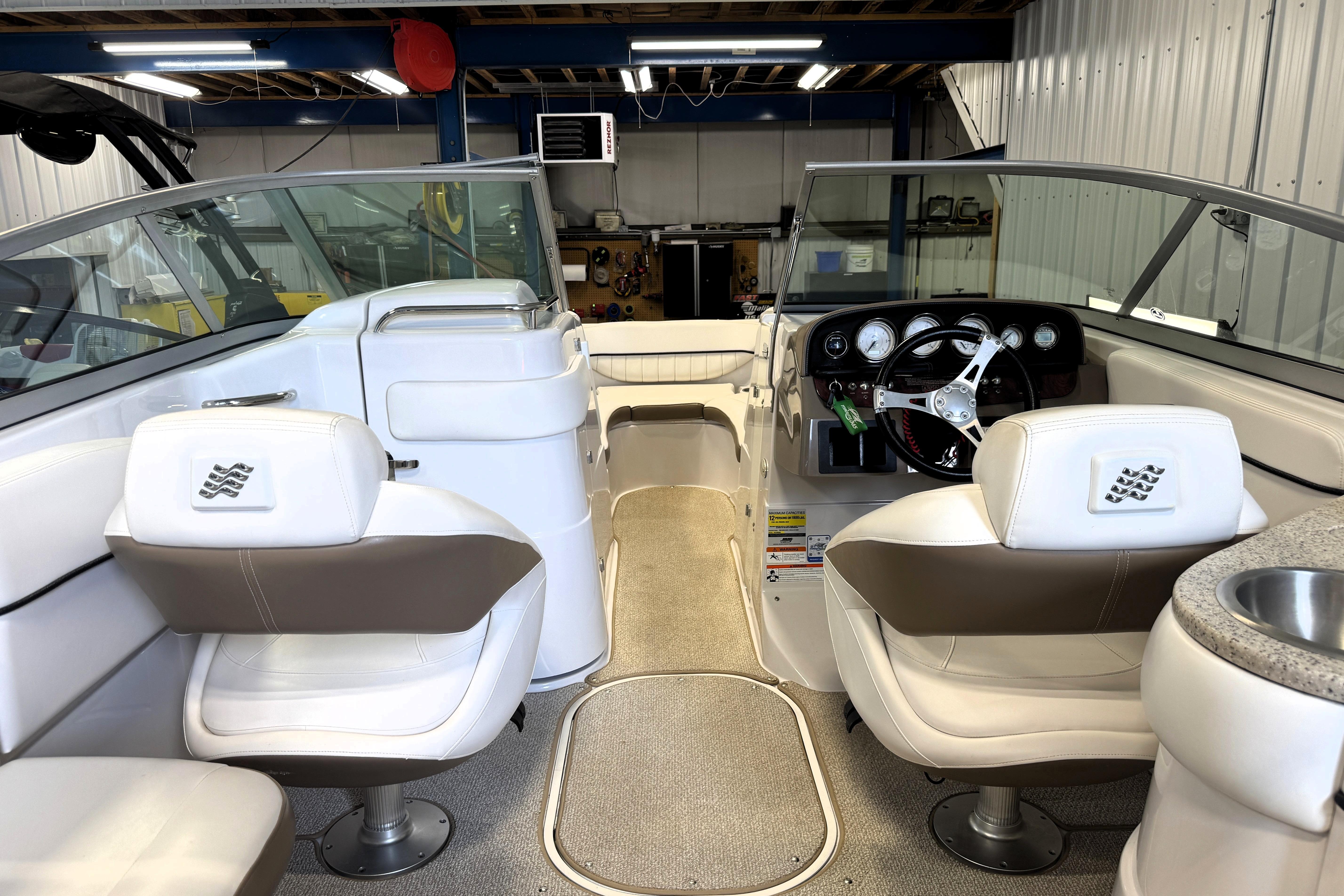 Interior of a 2008 Four Winns H240 boat with white seating and steering console.