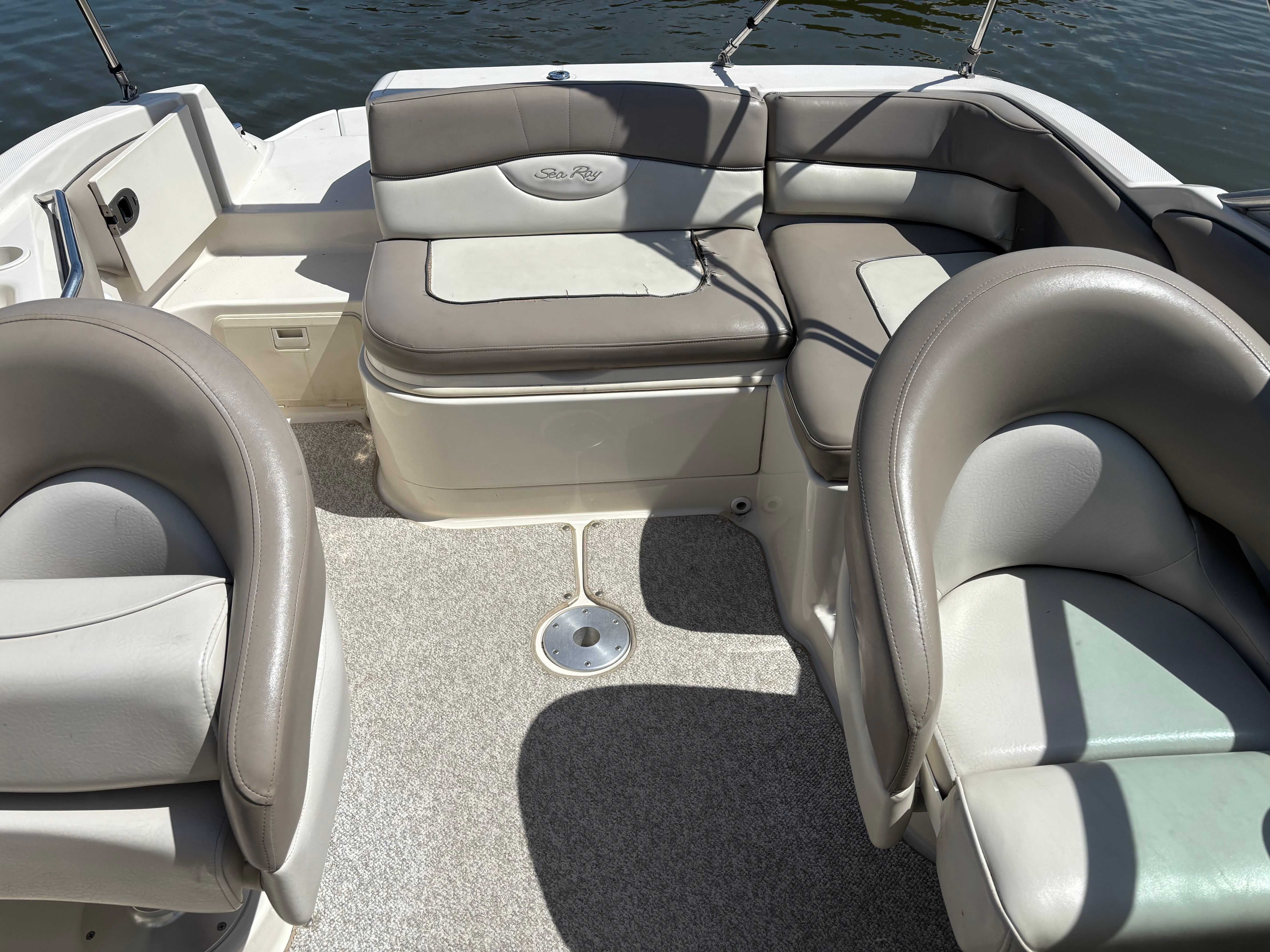 Interior of a Sea Ray 220 Sundeck boat with cushioned seating and carpeted floor.