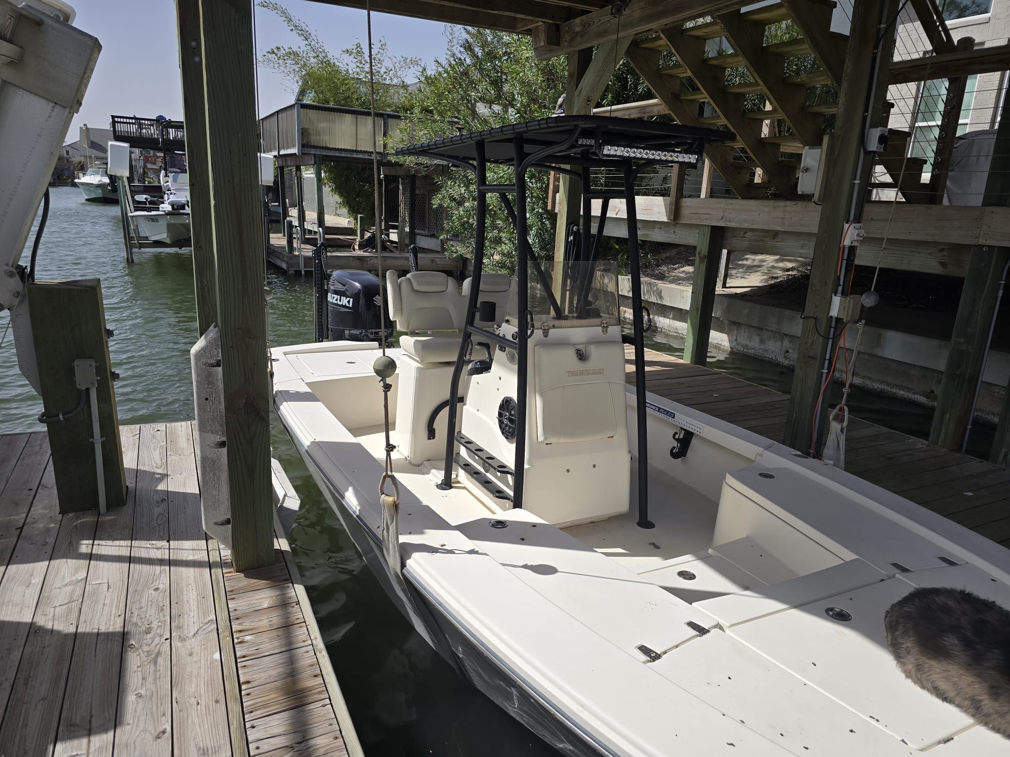 A white boat docked at a wooden pier in a calm canal.