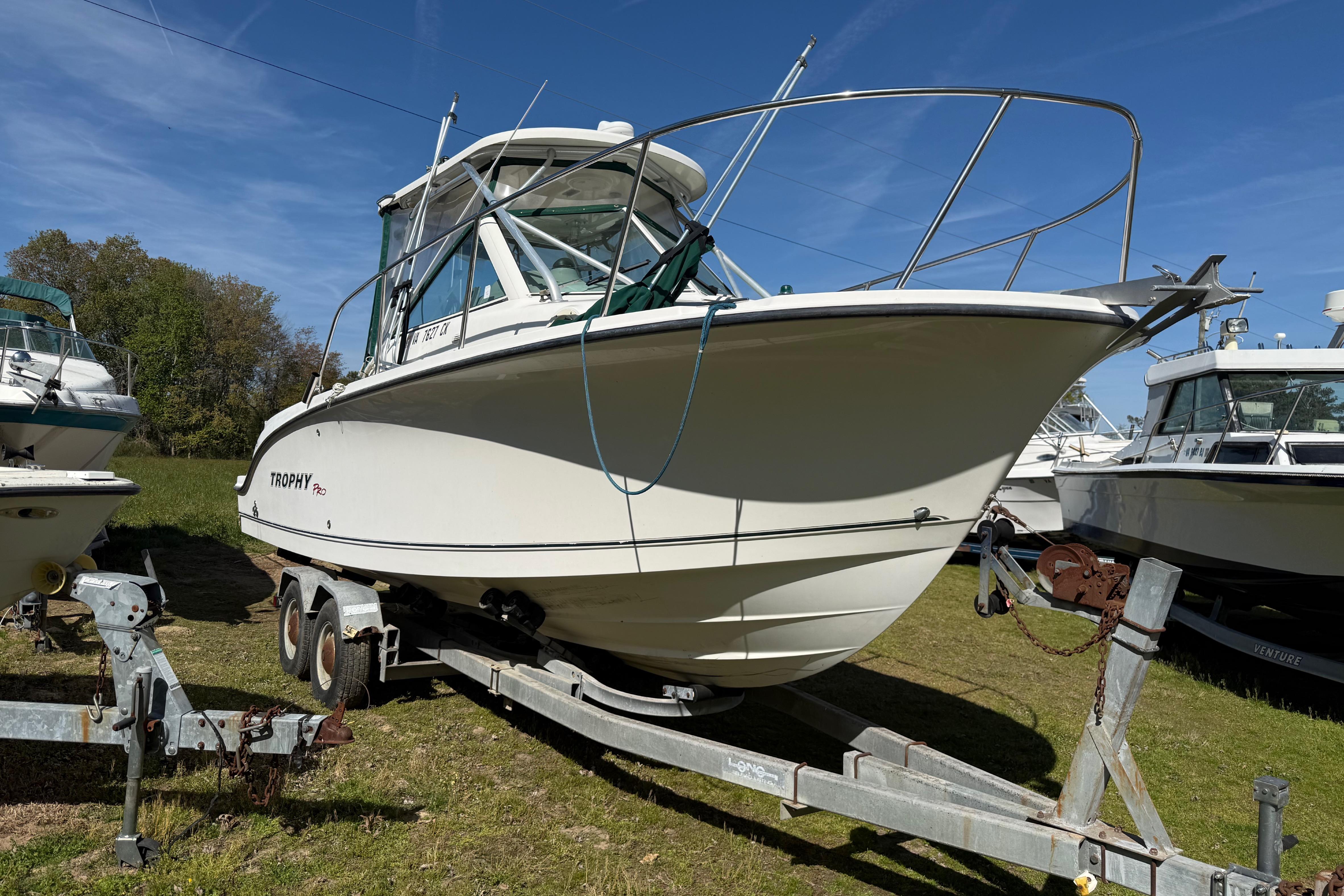 2006 Trophy 2502 Walkaround boat on trailer, parked outdoors under clear blue sky.