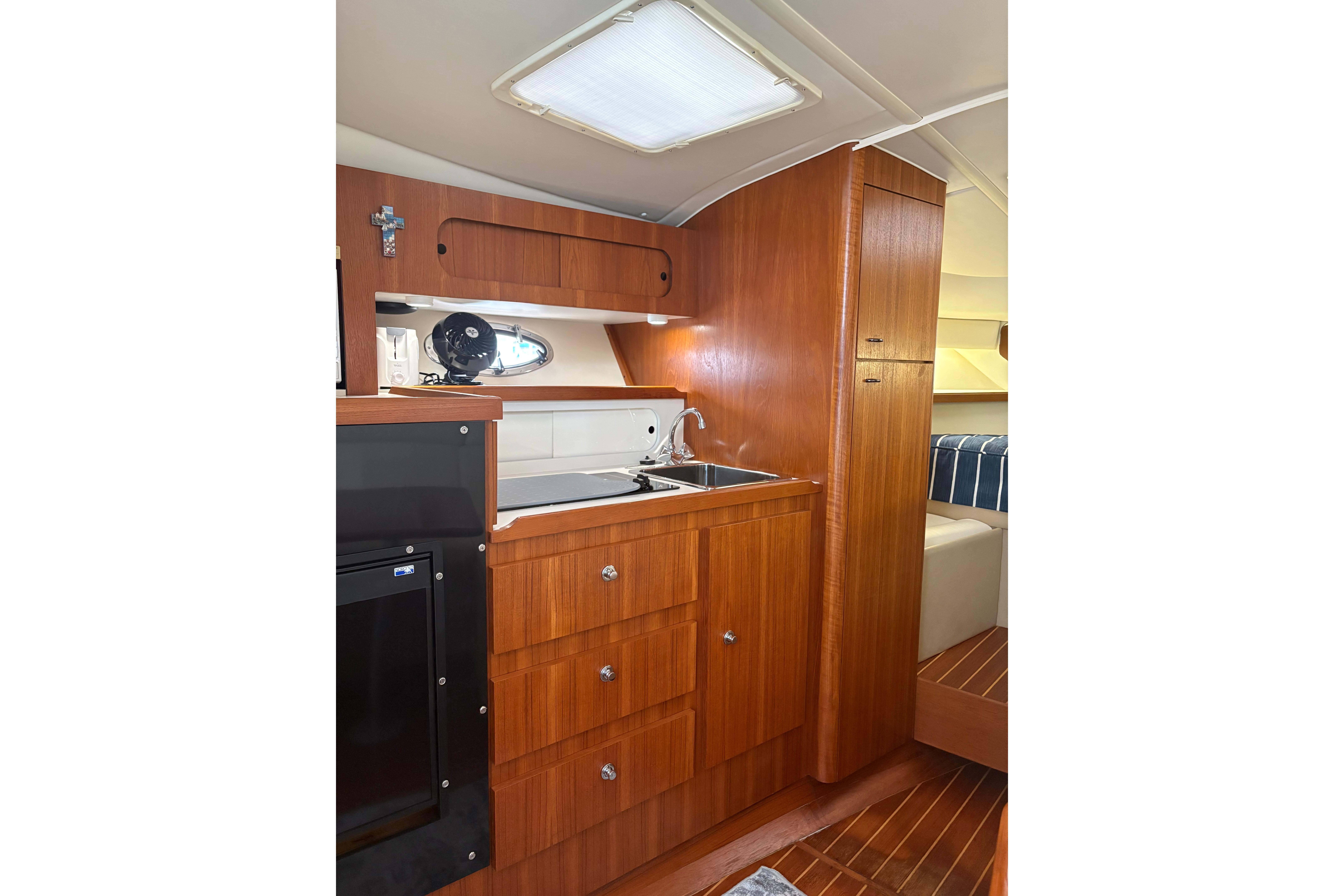 1999 Tiara Yachts 3100 Open interior with wooden cabinetry and compact kitchen area.