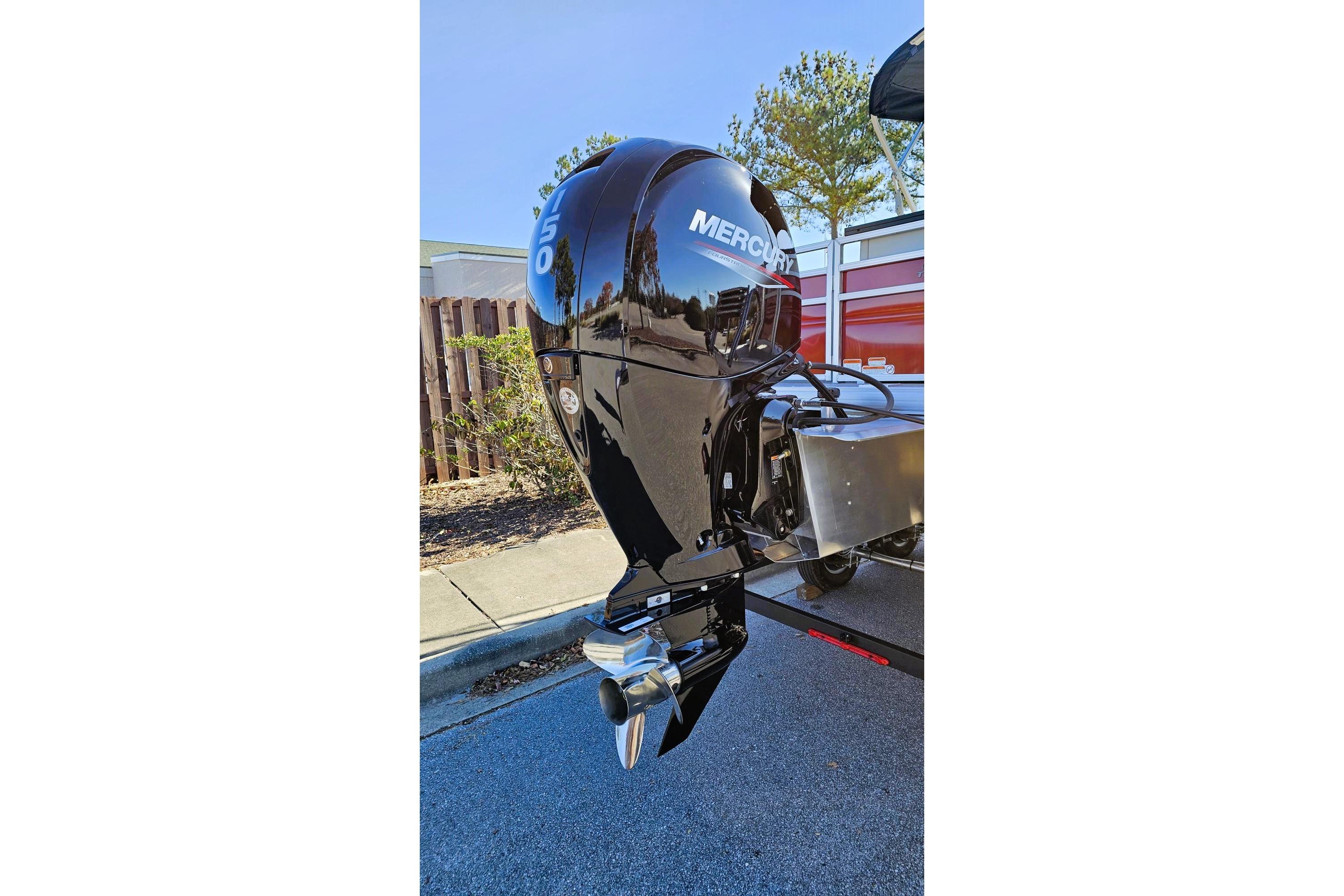 Outboard motor on a 2026 Sun Tracker Fishin' Barge 22 DLX, parked outdoors.