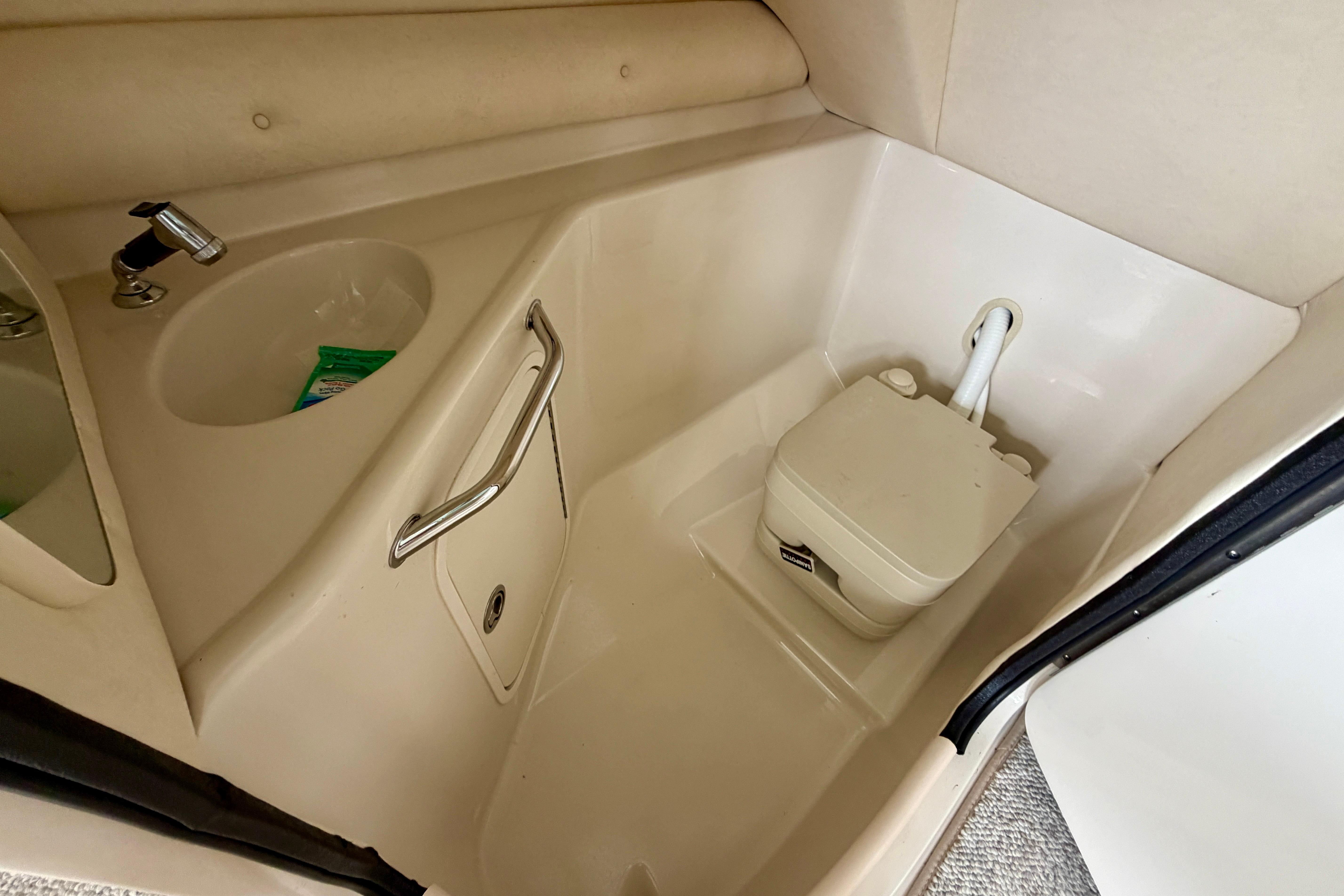 Interior of 2005 Sea Ray 240 Sundeck featuring compact marine toilet and sink.