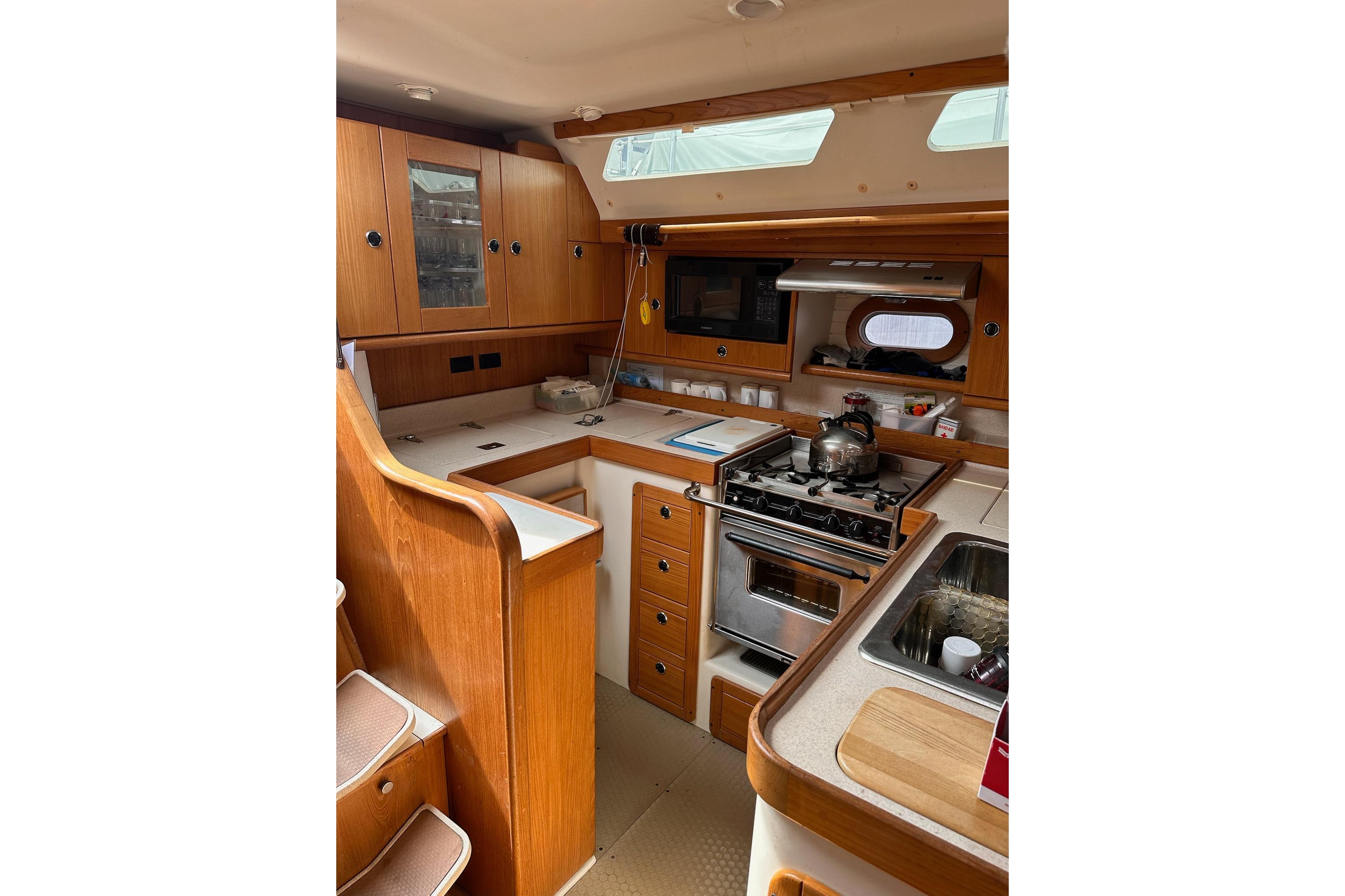 Interior of 2002 Catalina 470 yacht kitchen with wooden cabinetry and appliances.