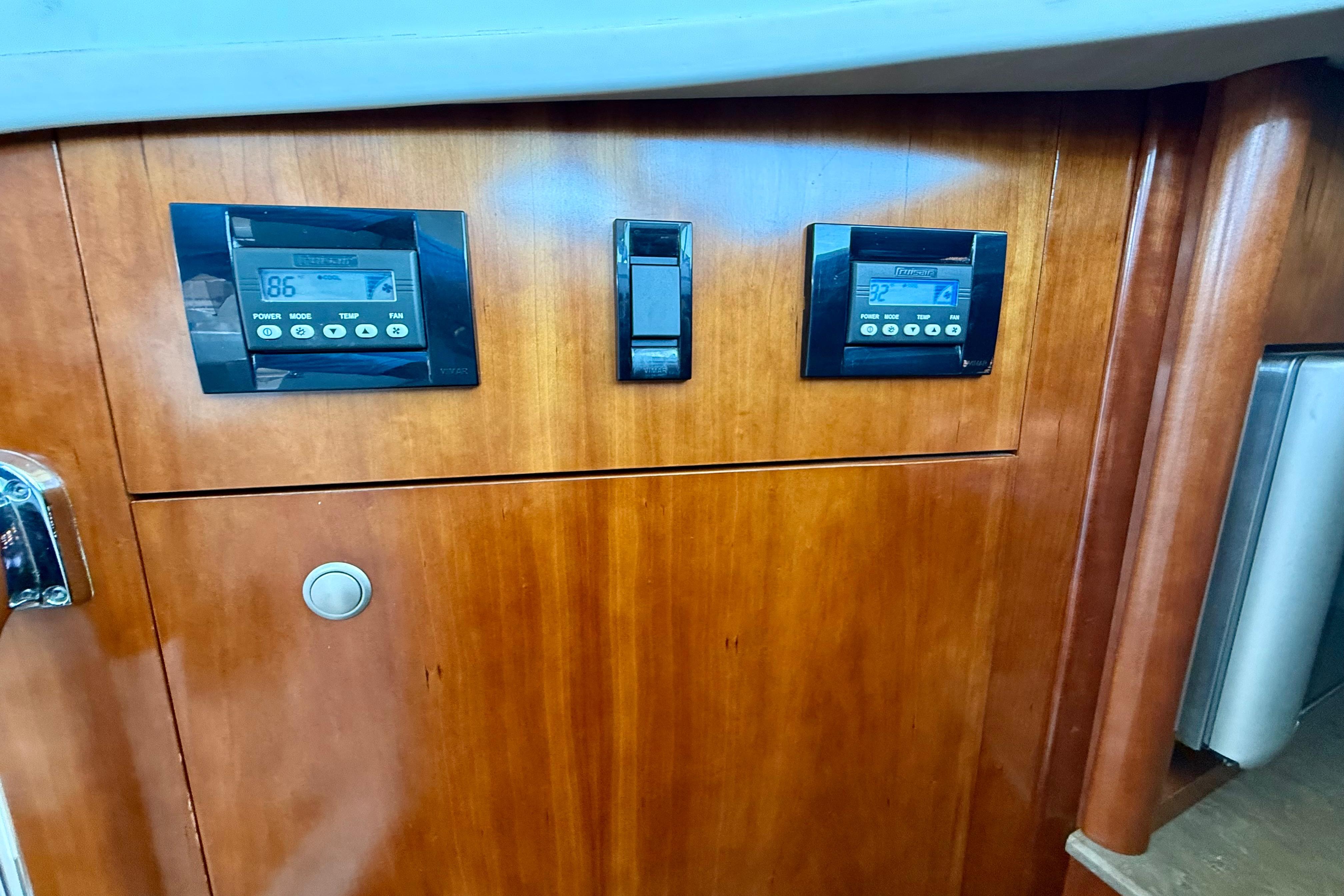Control panel on 2011 Cruisers Yachts 390 Sports Coupe, featuring wooden cabinetry and digital displays.