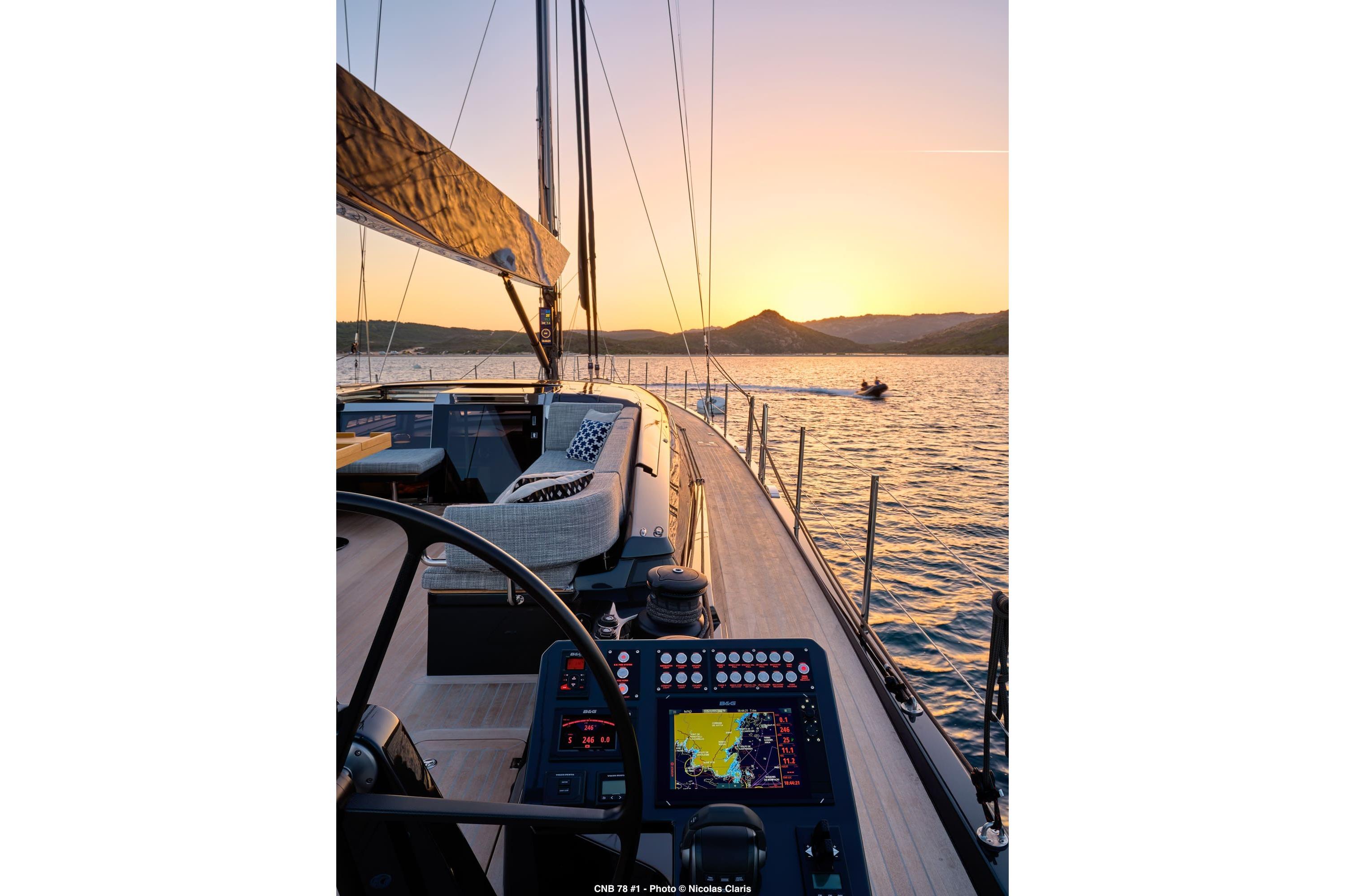 Luxurious CNB 78 yacht sailing at sunset, featuring modern navigation controls, 2027 model.