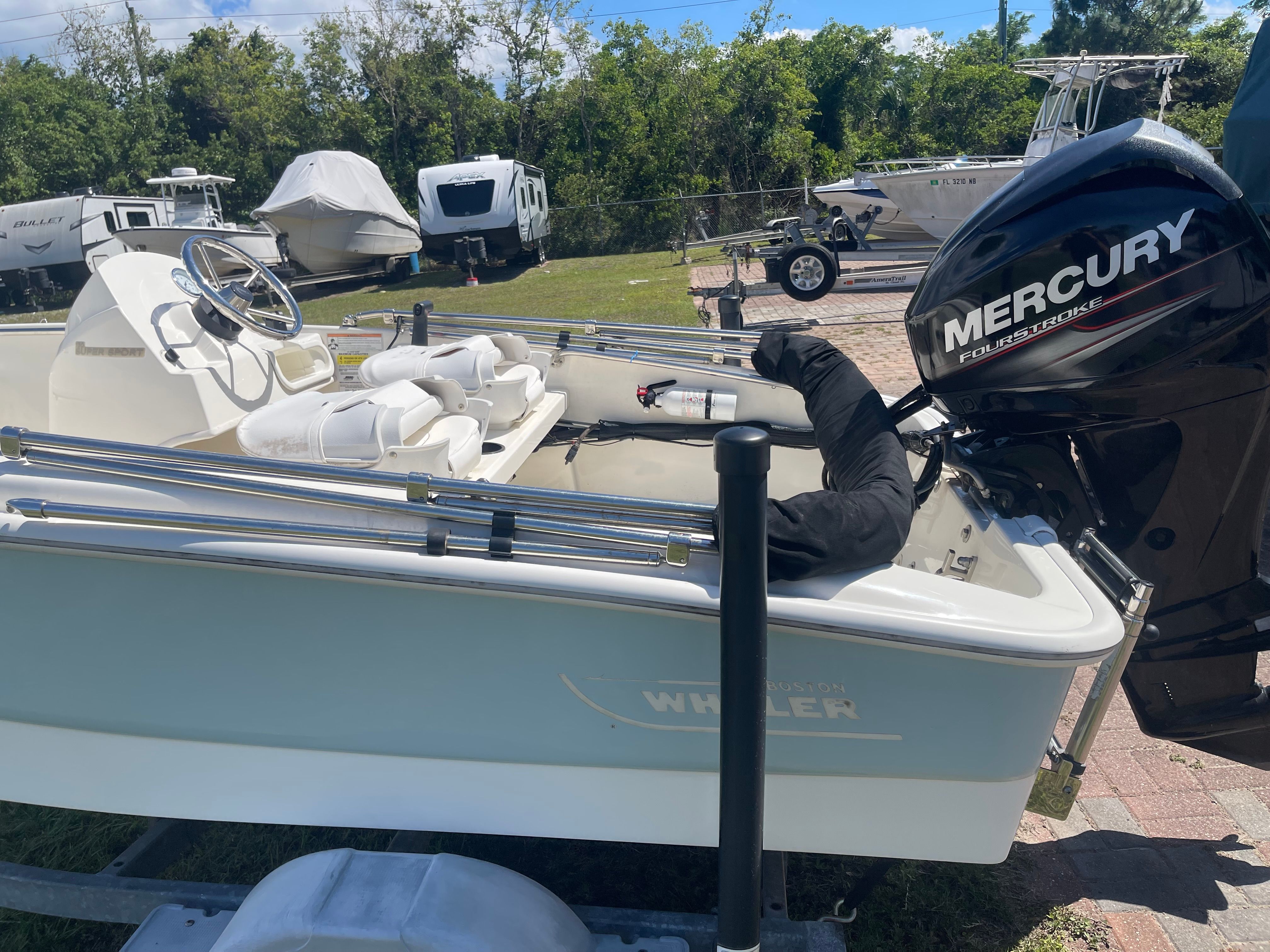 A 2017 Boston Whaler 130 Super Sport with a Mercury outboard motor, parked on a trailer.