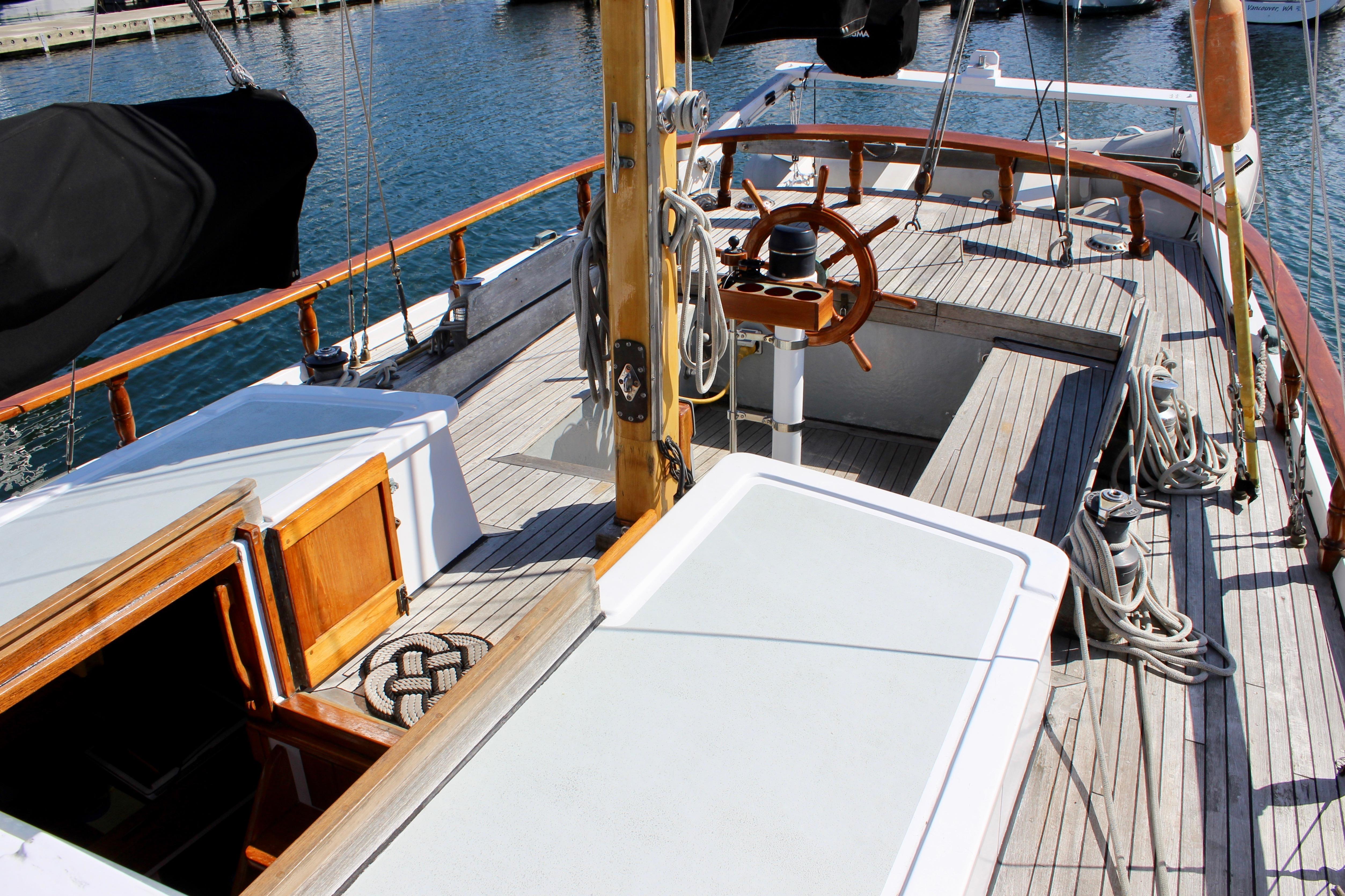 1975 William Garden Porpoise sailboat deck with wooden steering wheel and nautical ropes.