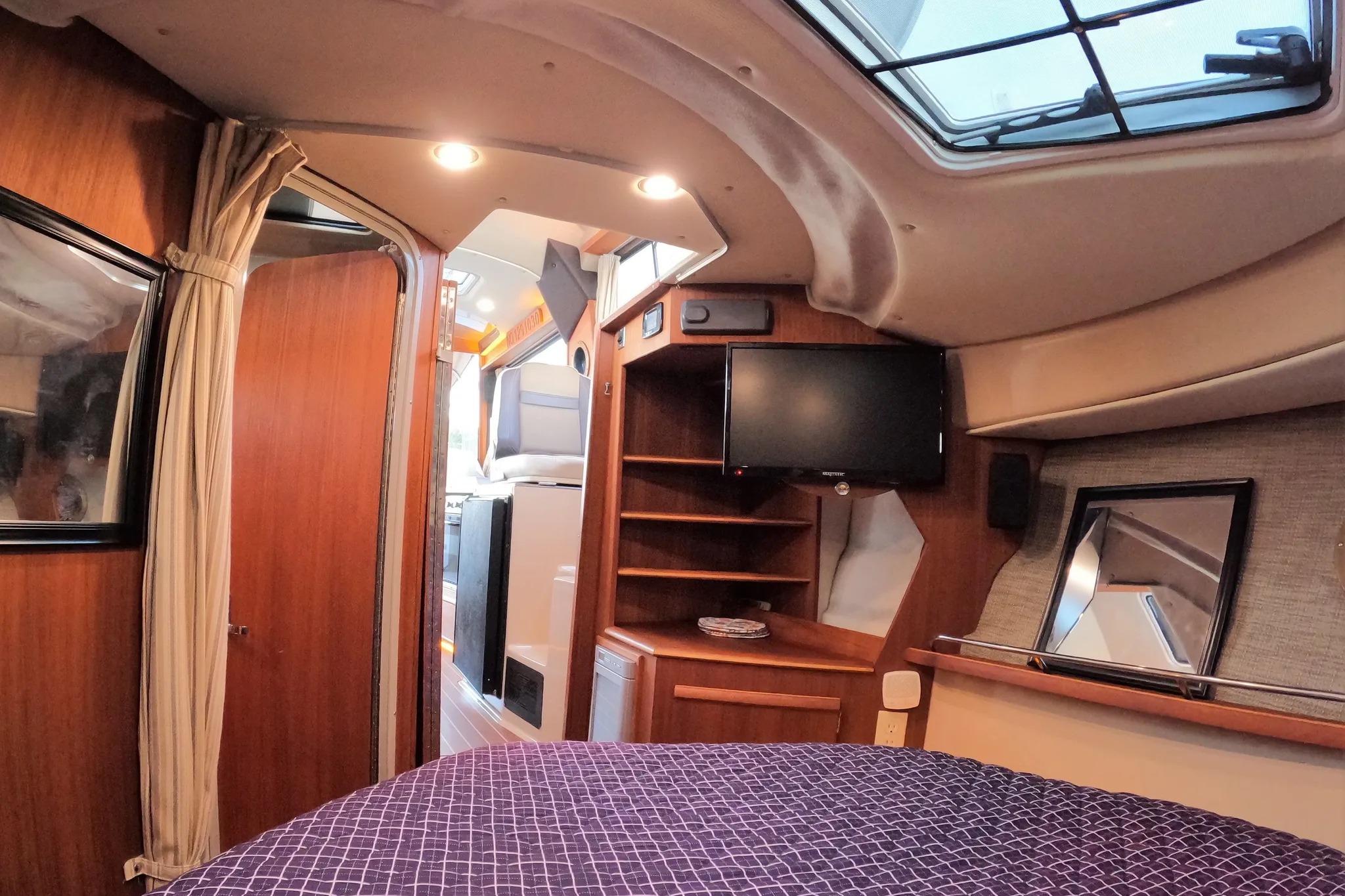 2015 Ranger Tugs R-29 S interior cabin with cozy bed, TV, and wooden accents.