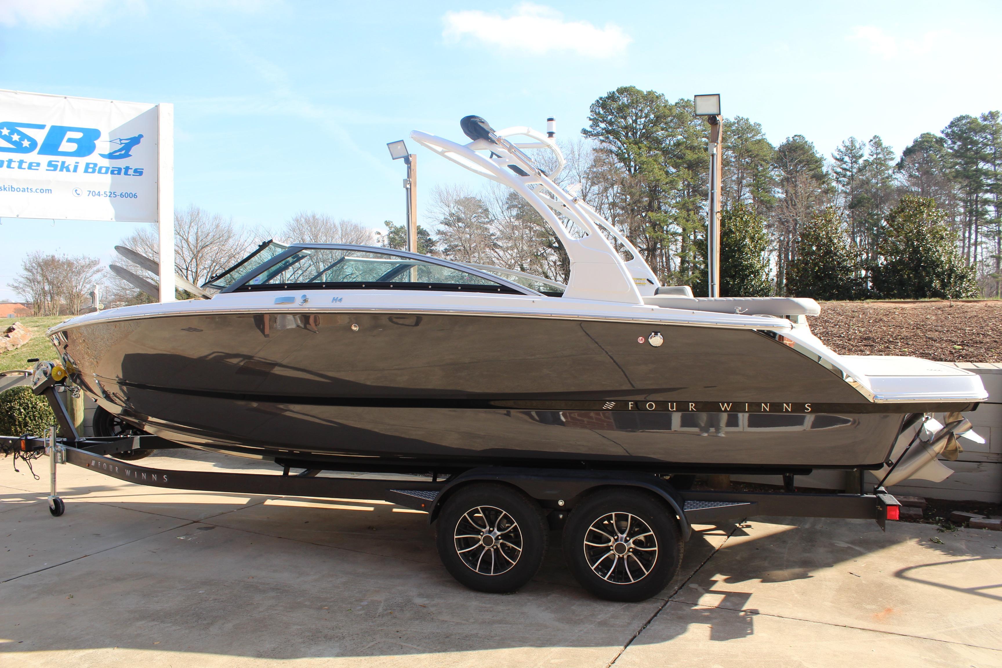 2026 Four Winns H4 boat on trailer at dealership, sunny day.