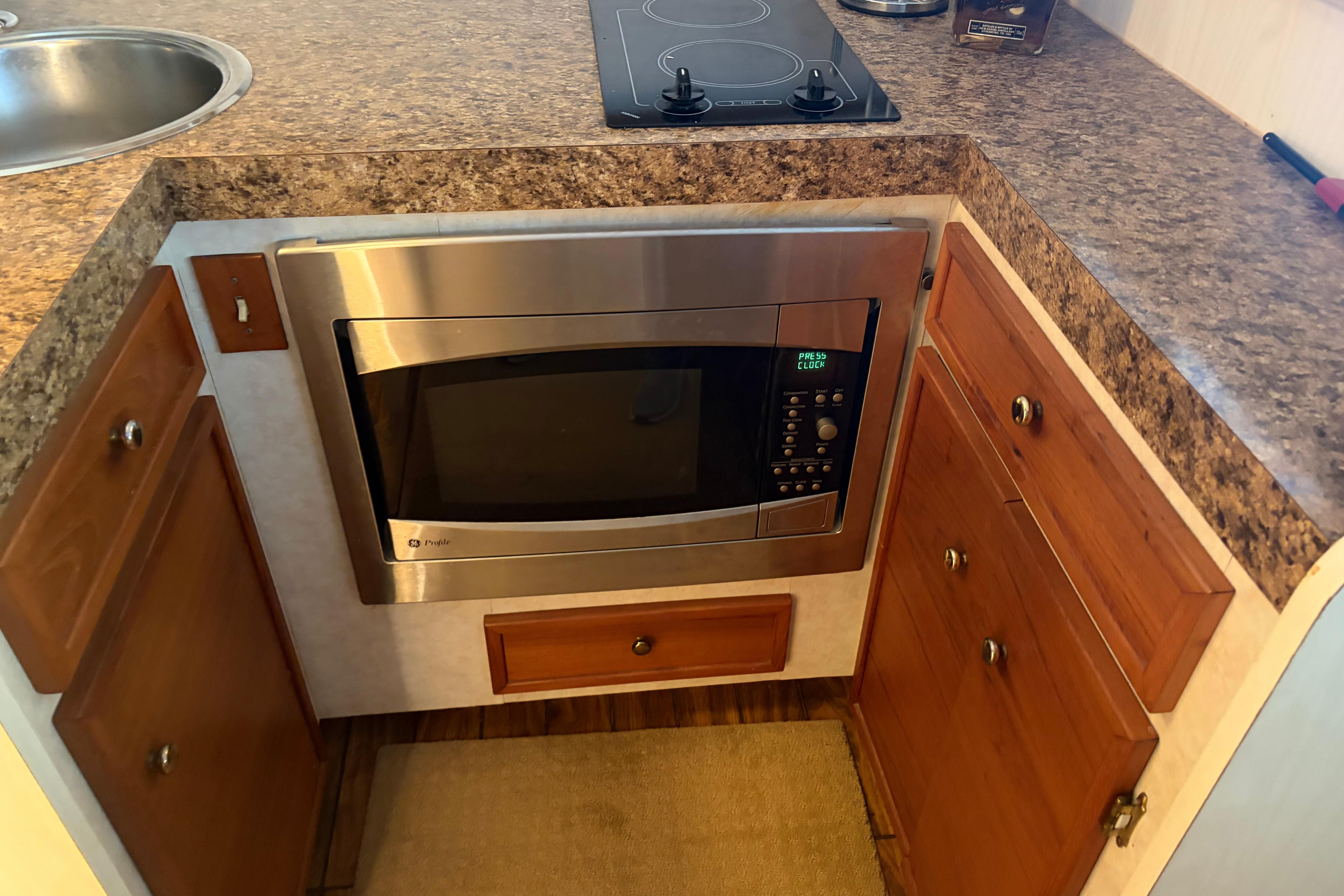 1971 Chris-Craft 42 Commander kitchen with microwave, stovetop, and wooden cabinetry.